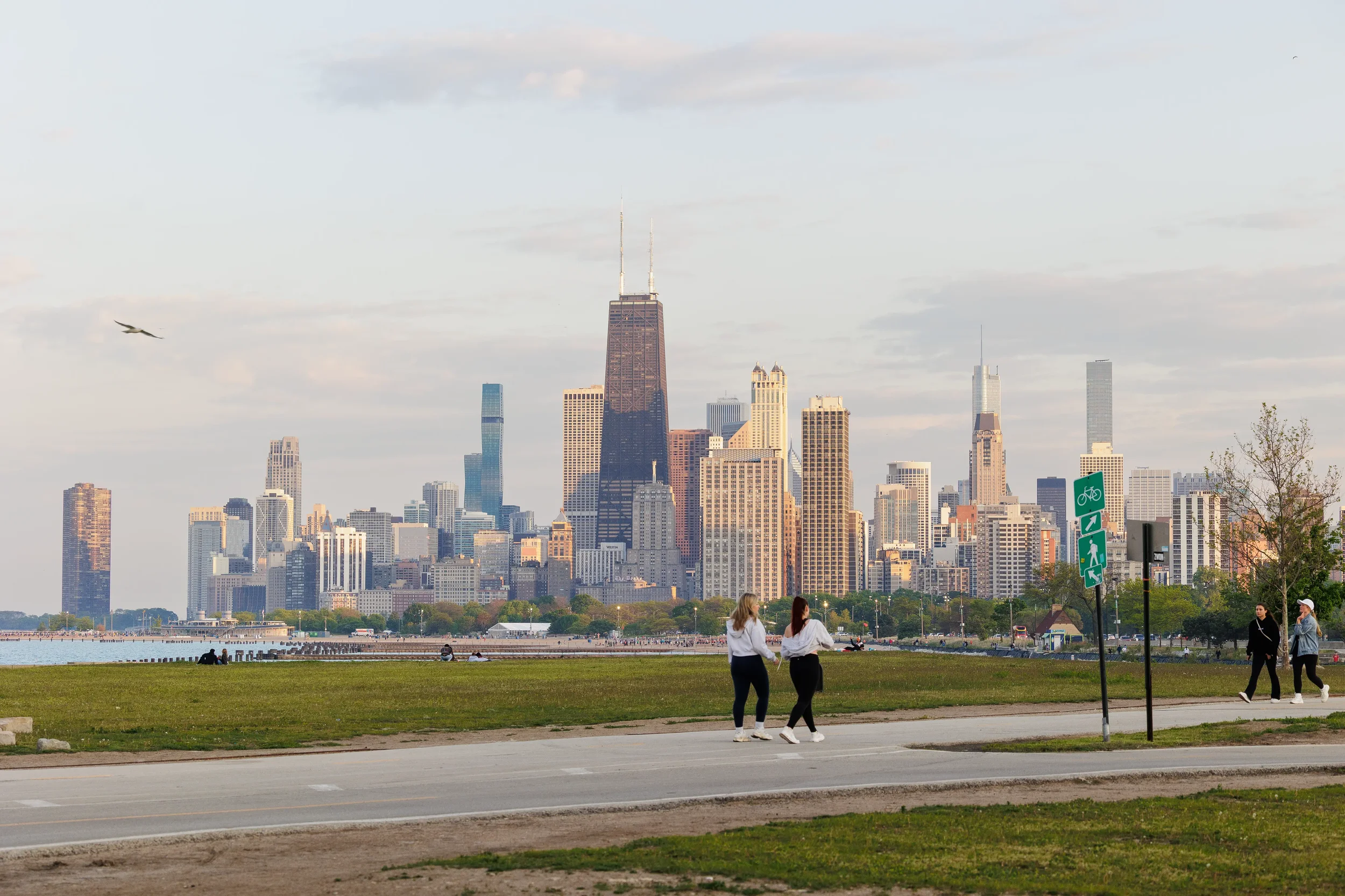 Pedestrians walk along lakefront path with Chicago skyline in golden hour light