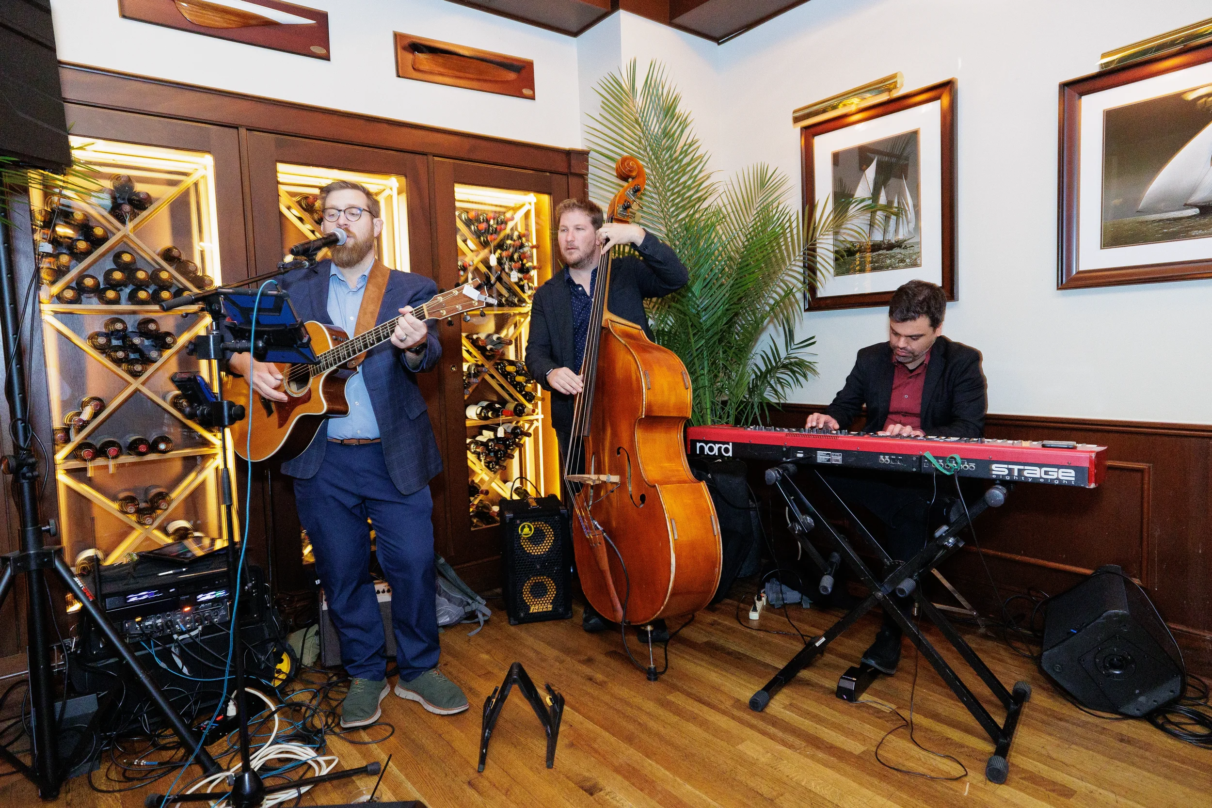 A guitarist, bass player, and keyboardist perform live in a dimly lit venue for a Chicago conference.