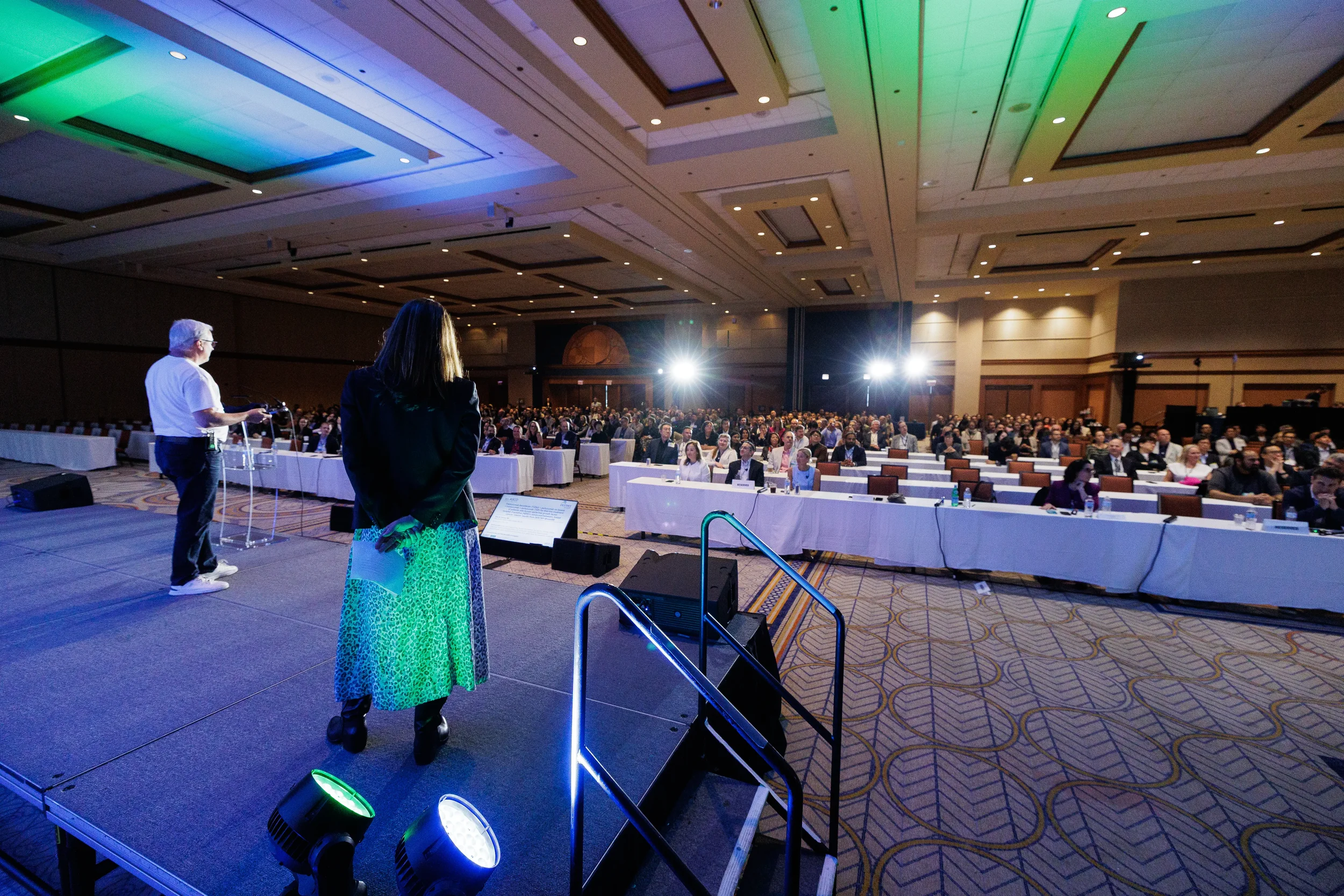 Wide view of speakers addressing seated audience in ballroom at Orlando corporate conference