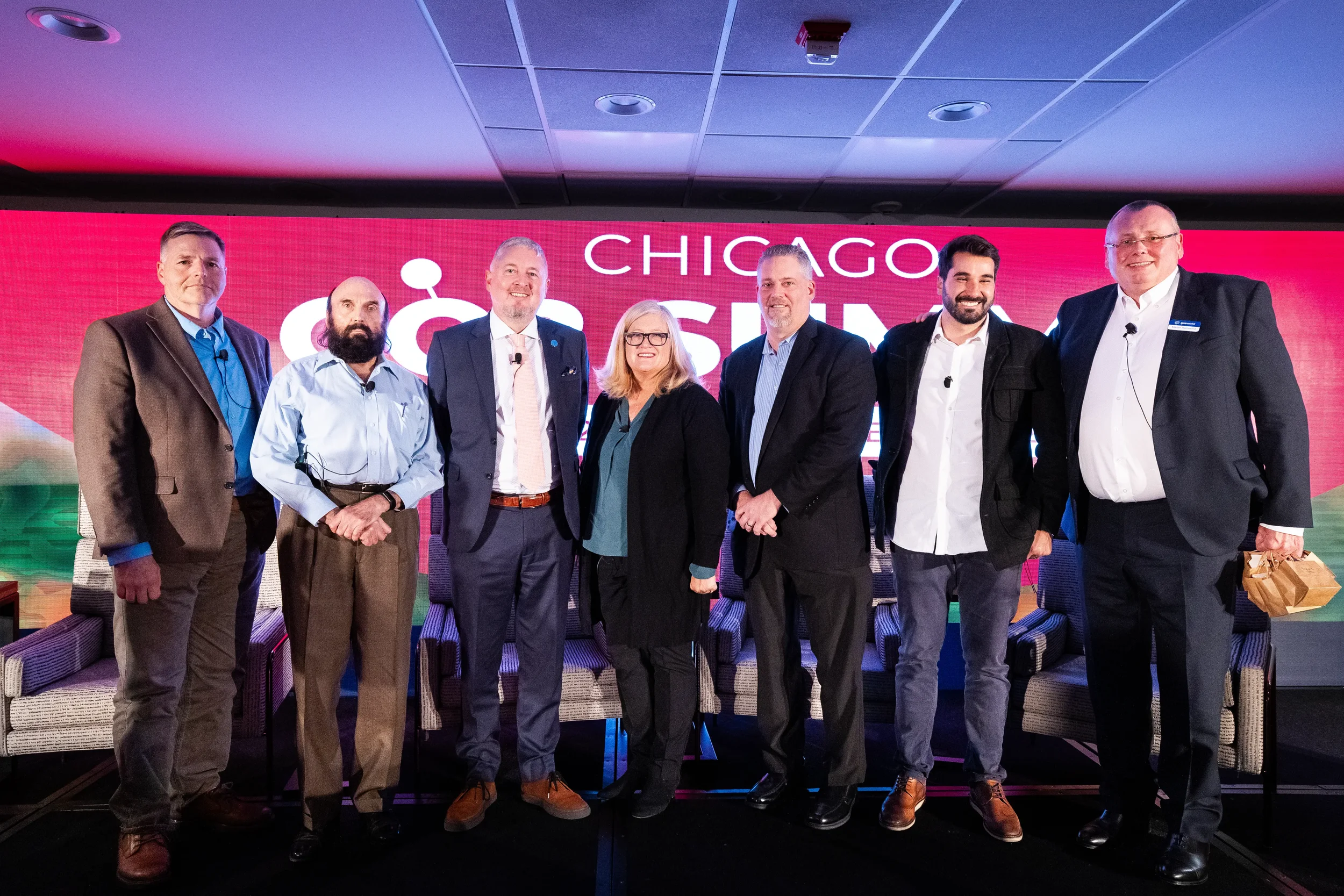 Panel speakers pose for group photo on stage after discussion at Orlando industry summit