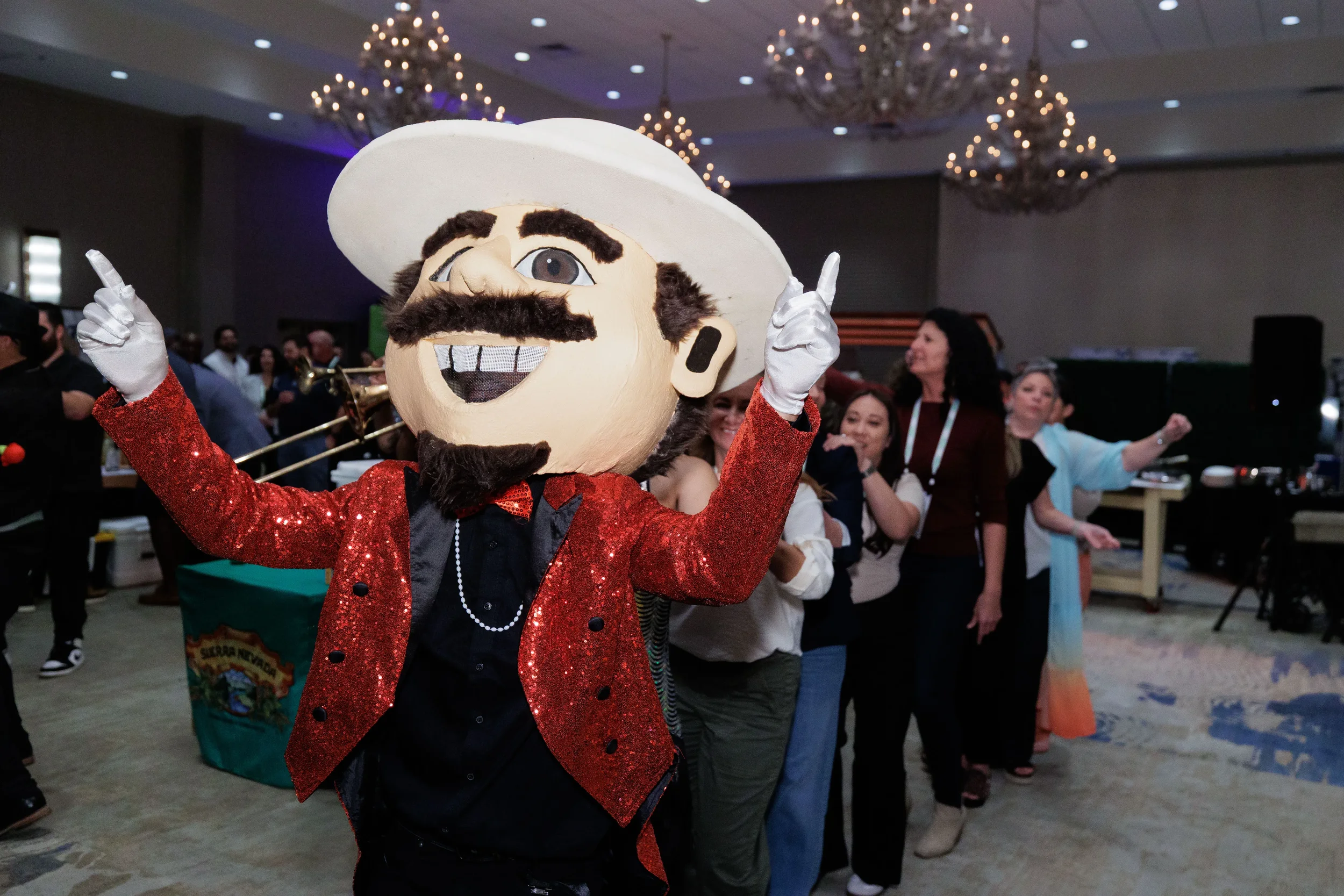 Costumed mascot character leads dancing attendees in ballroom at Chicago corporate conference gala event