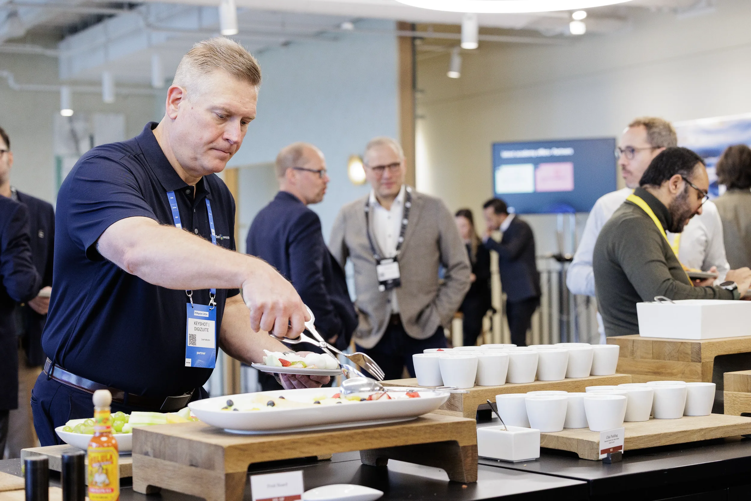 Attendee serves fruit at breakfast buffet while others network at Chicago industry conference