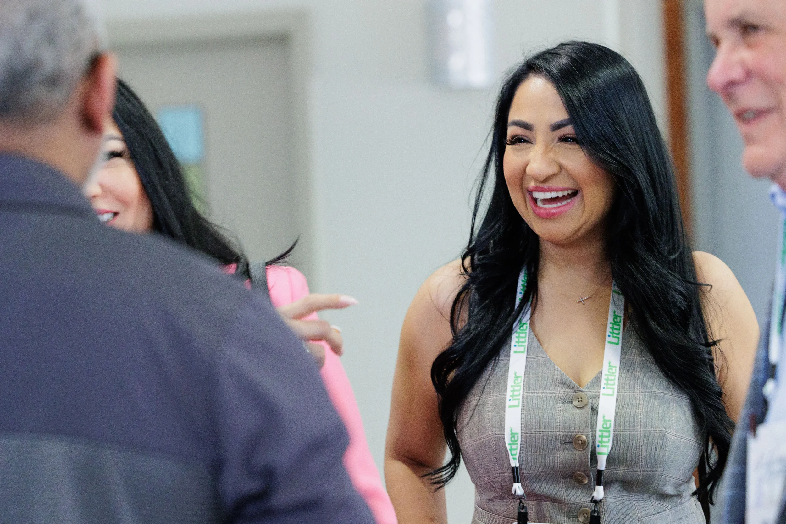 Female attendee with lanyard laughs warmly during networking reception at Chicago corporate conference