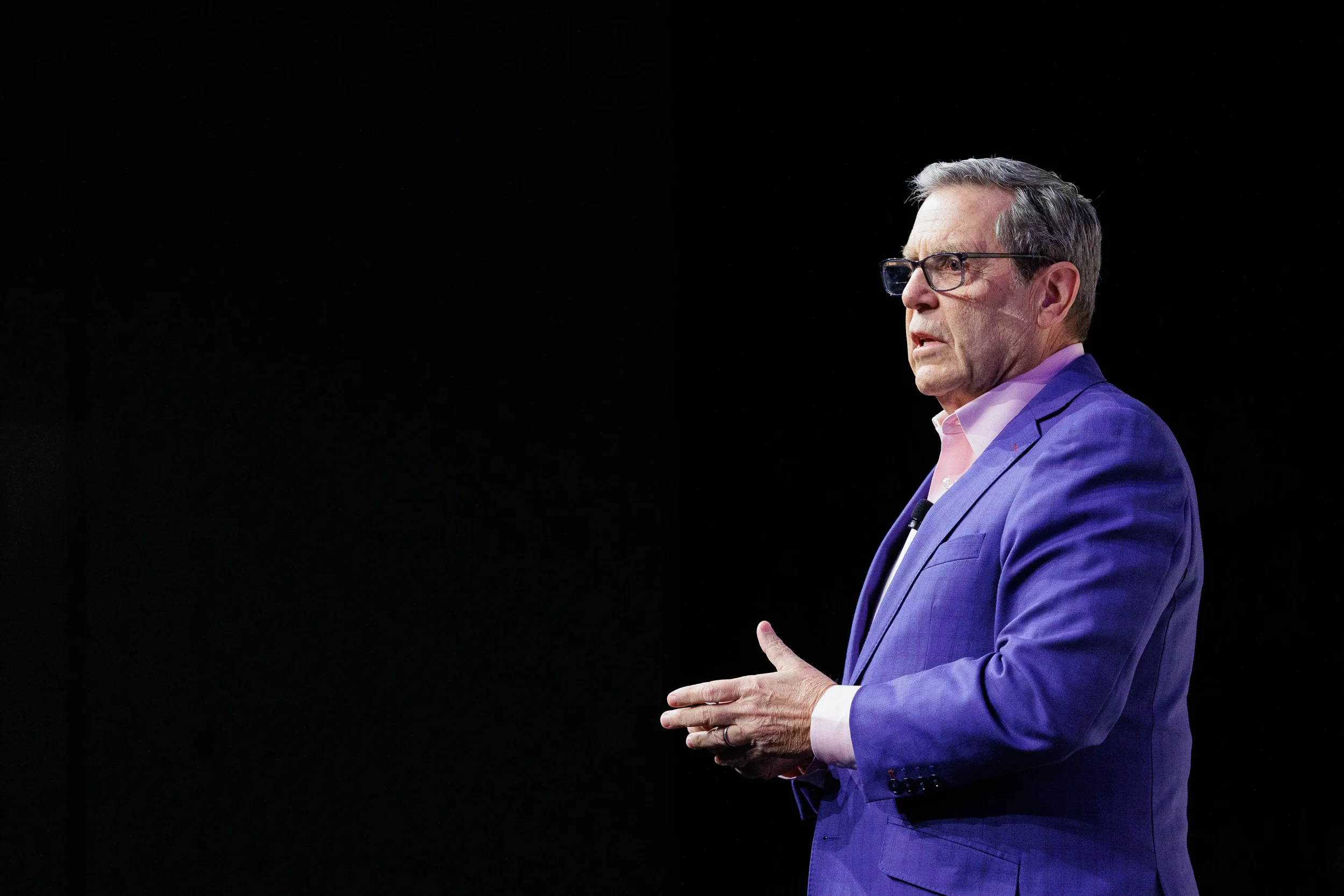 Executive speaker presents on dramatically lit stage at Chicago industry conference