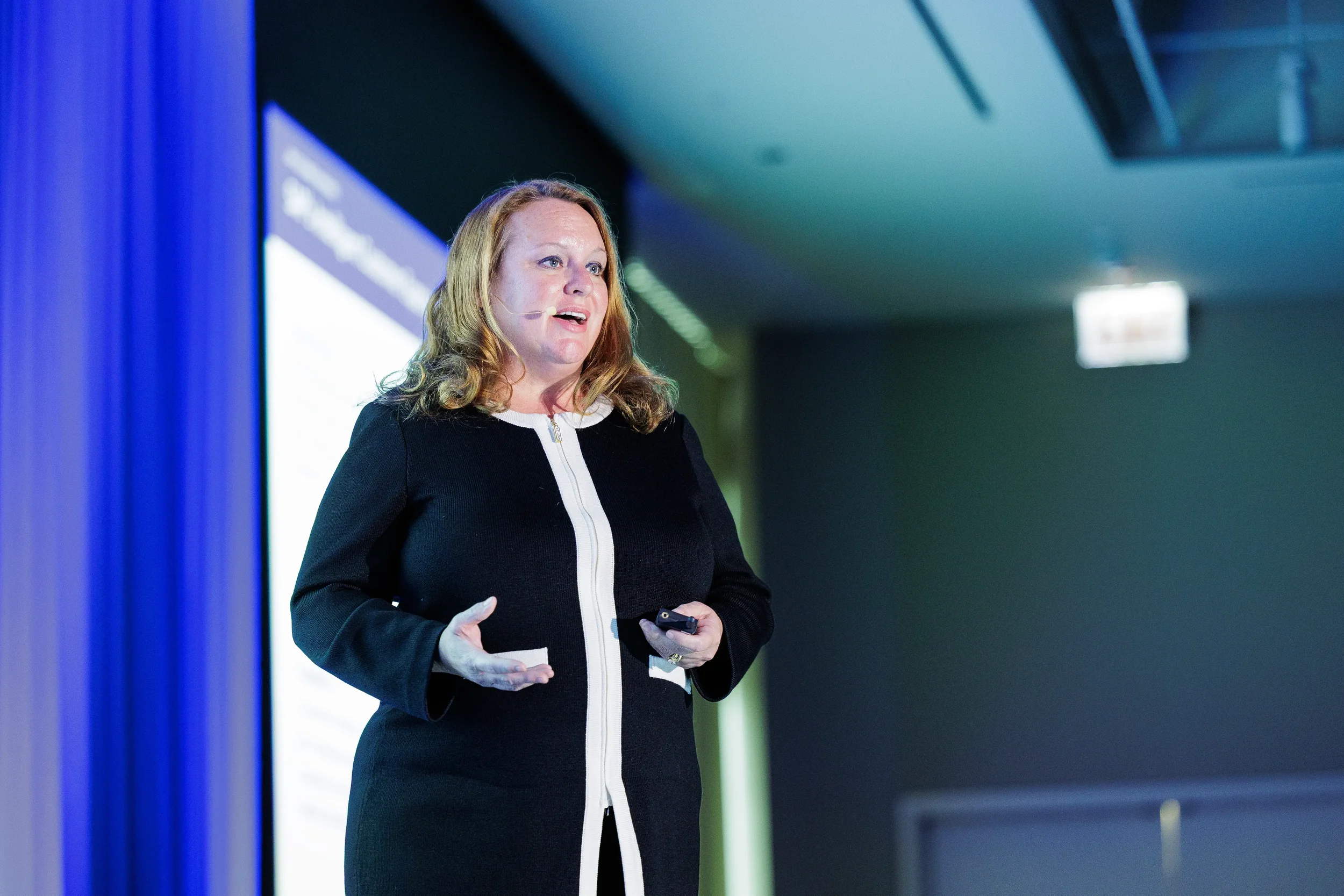 Speaker in black jacket with headset microphone presents on stage at Orlando corporate conference