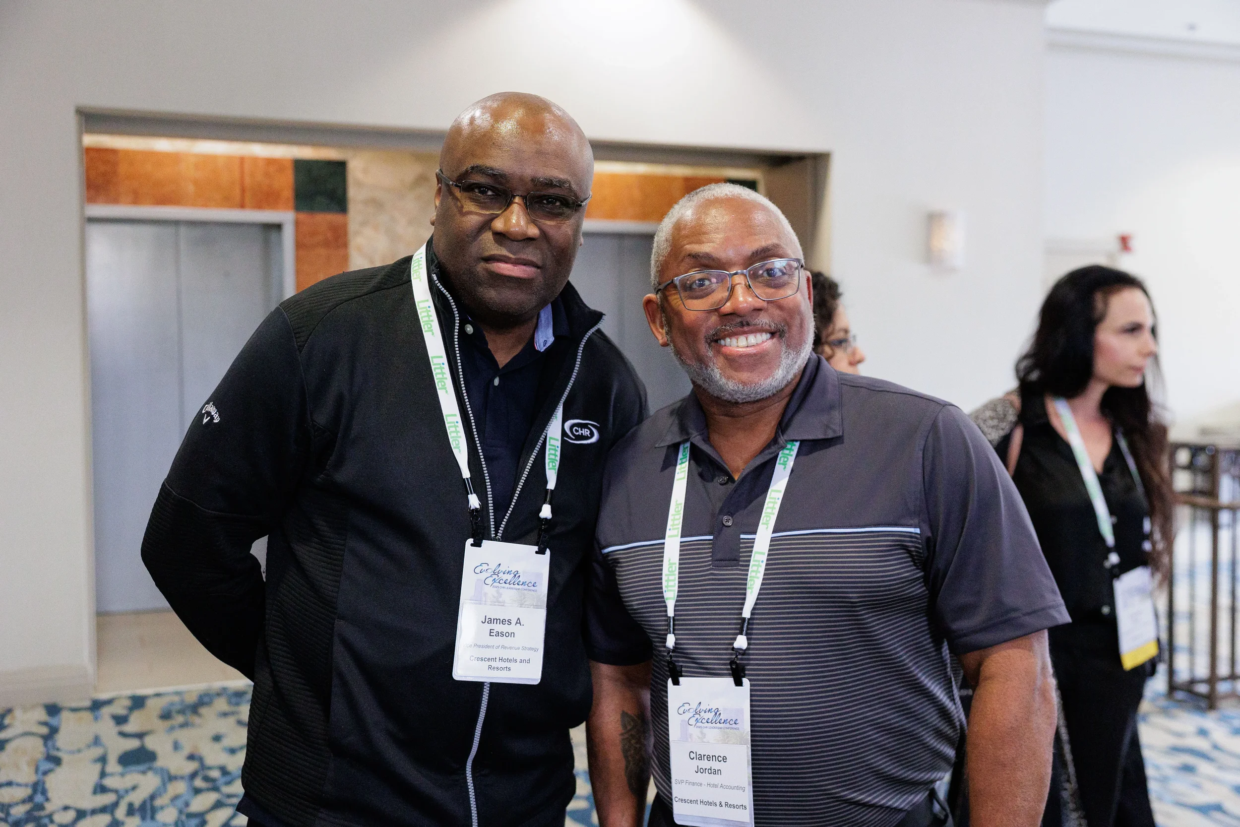 Two male attendees with lanyards smile together for photo in Chicago corporate conference lobby