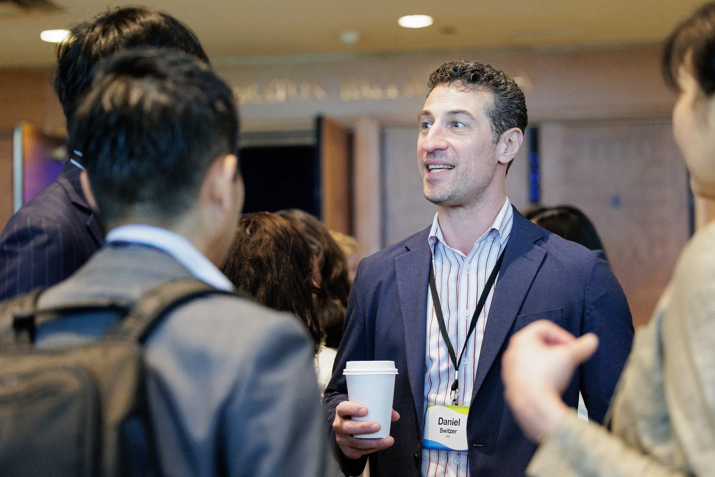 Attendee holds coffee cup while chatting with colleagues during networking break at Orlando corporate event