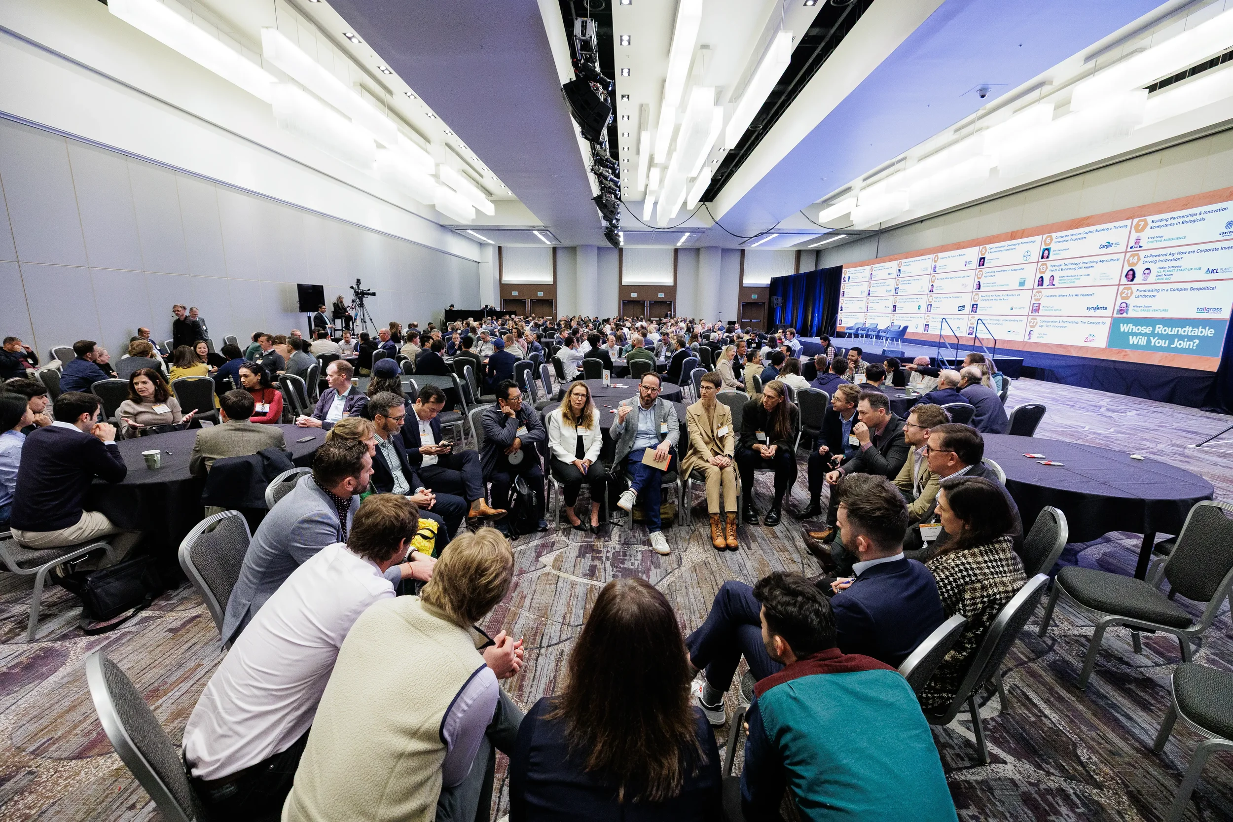 Wide shot of attendees in roundtable discussion groups across ballroom at Chicago corporate conference