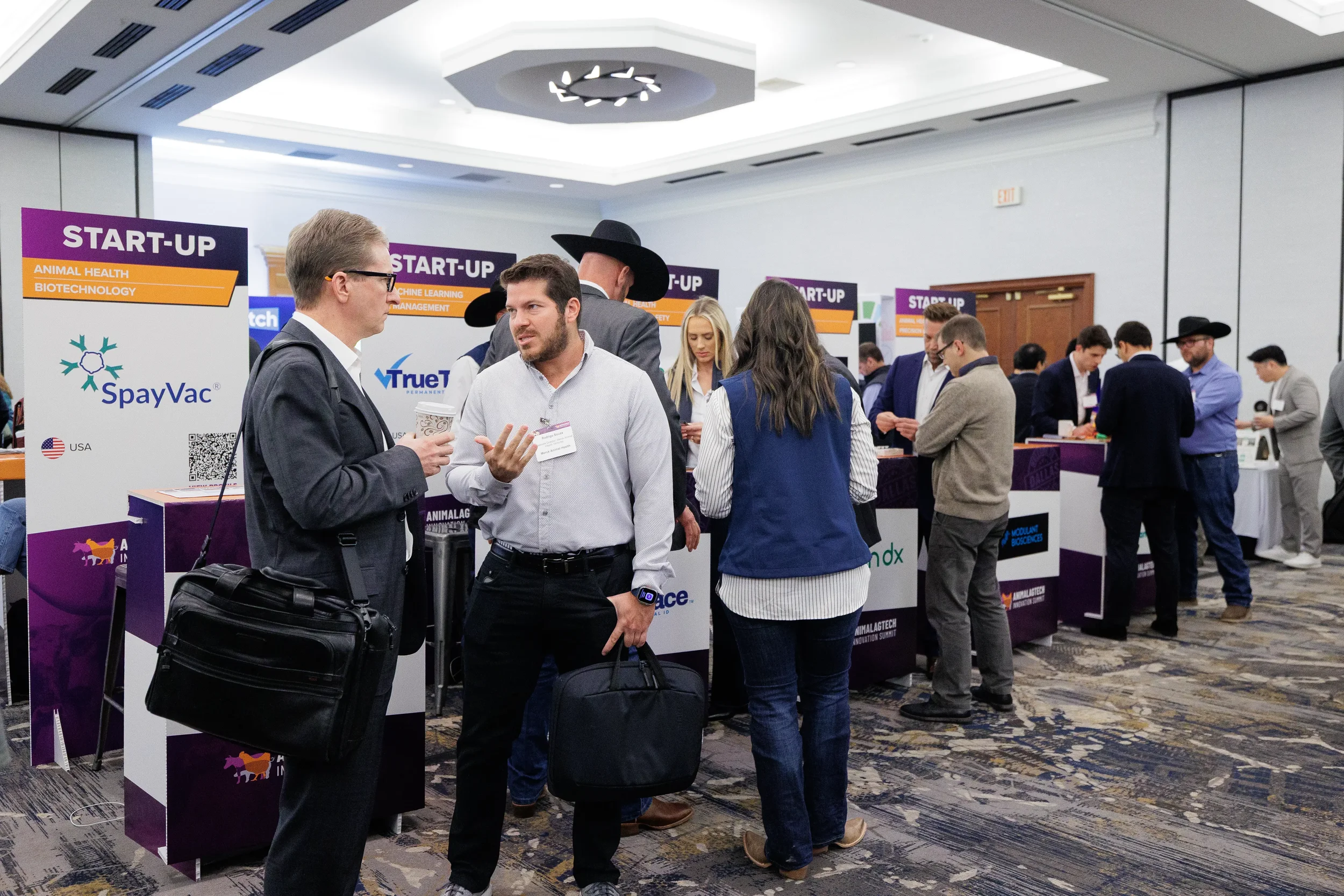 Attendees converse near startup exhibitor booths on expo floor at Orlando conference