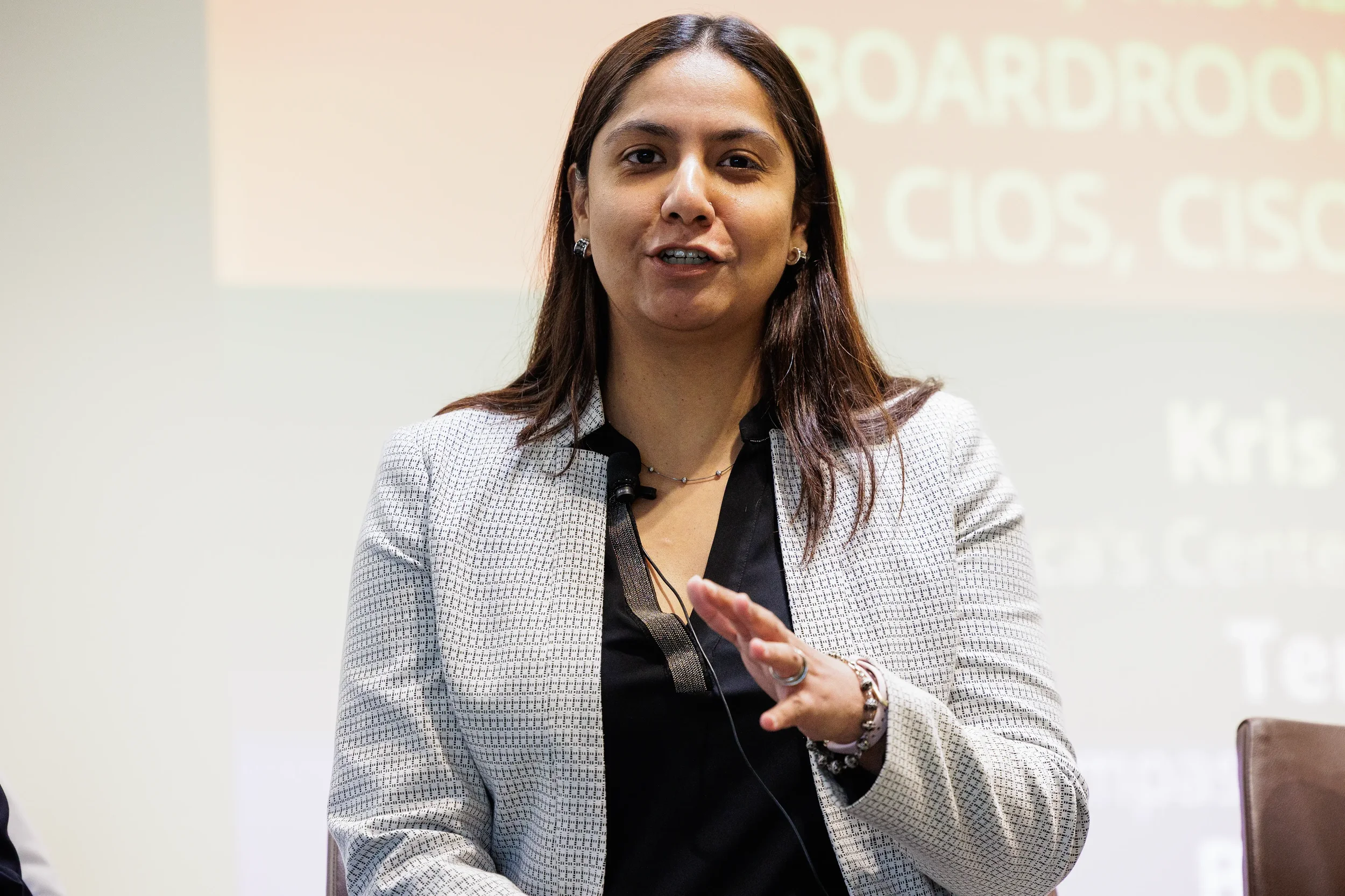 Female panelist gestures while speaking on stage in front of projection screen at Orlando industry conference