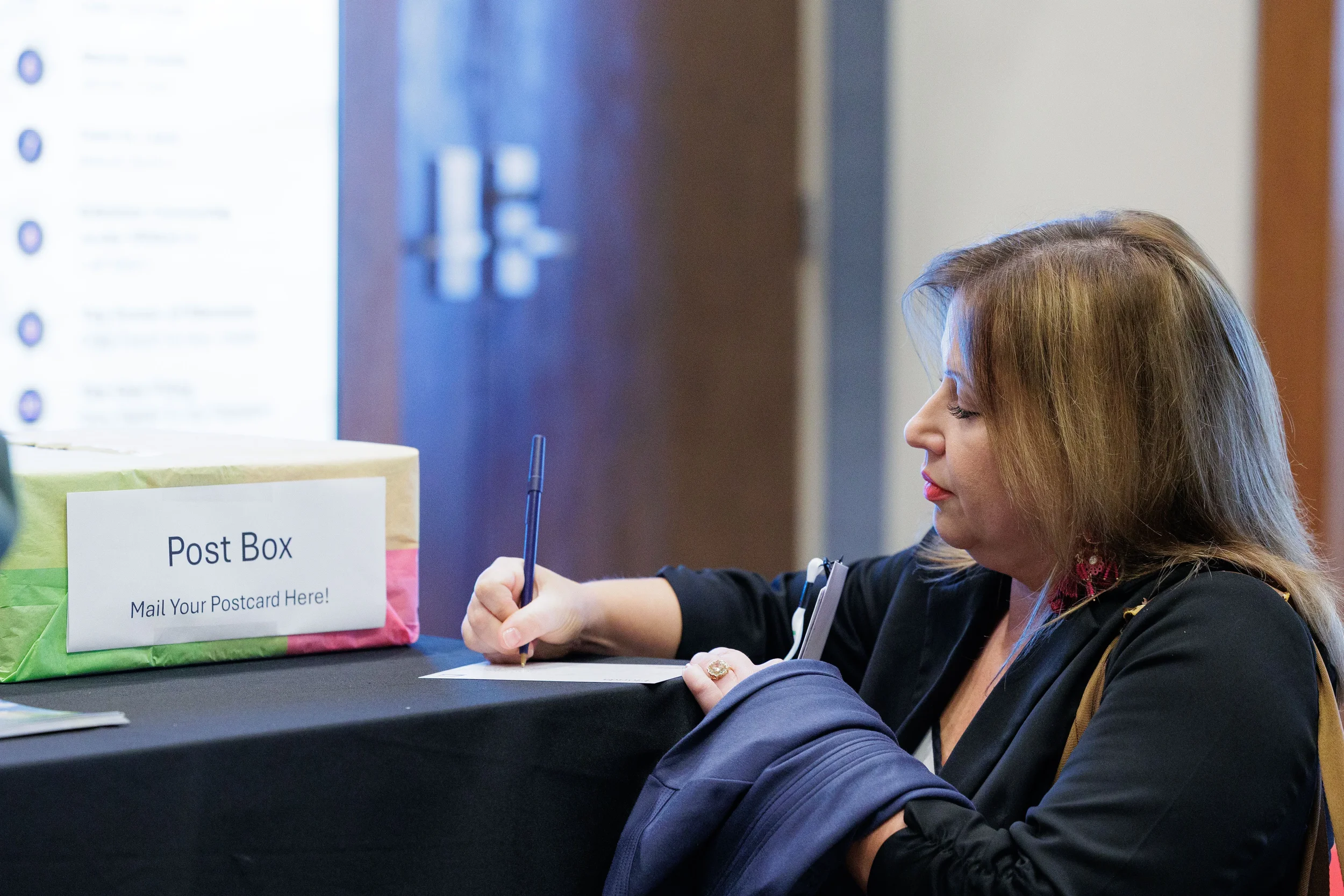 Female attendee writes postcard at interactive activity table during Chicago corporate conference