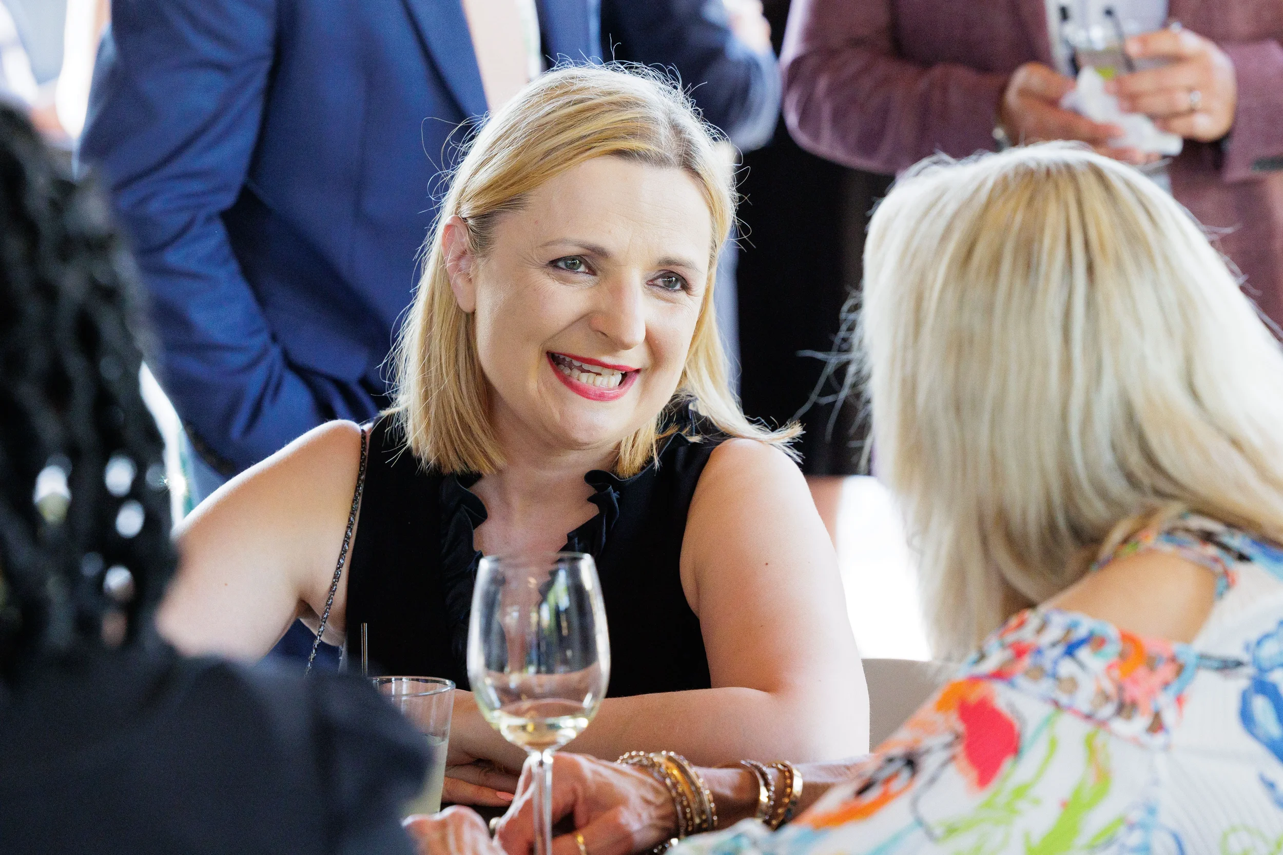 Smiling female attendee holds wine glass while networking at Chicago corporate conference outdoor reception