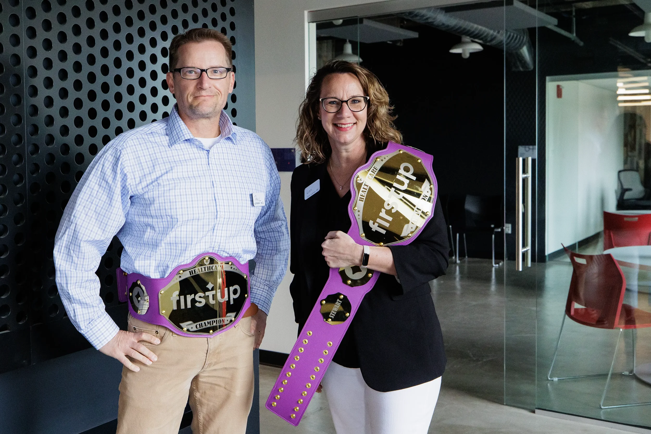 Two attendees pose with branded champion belts at Orlando corporate event