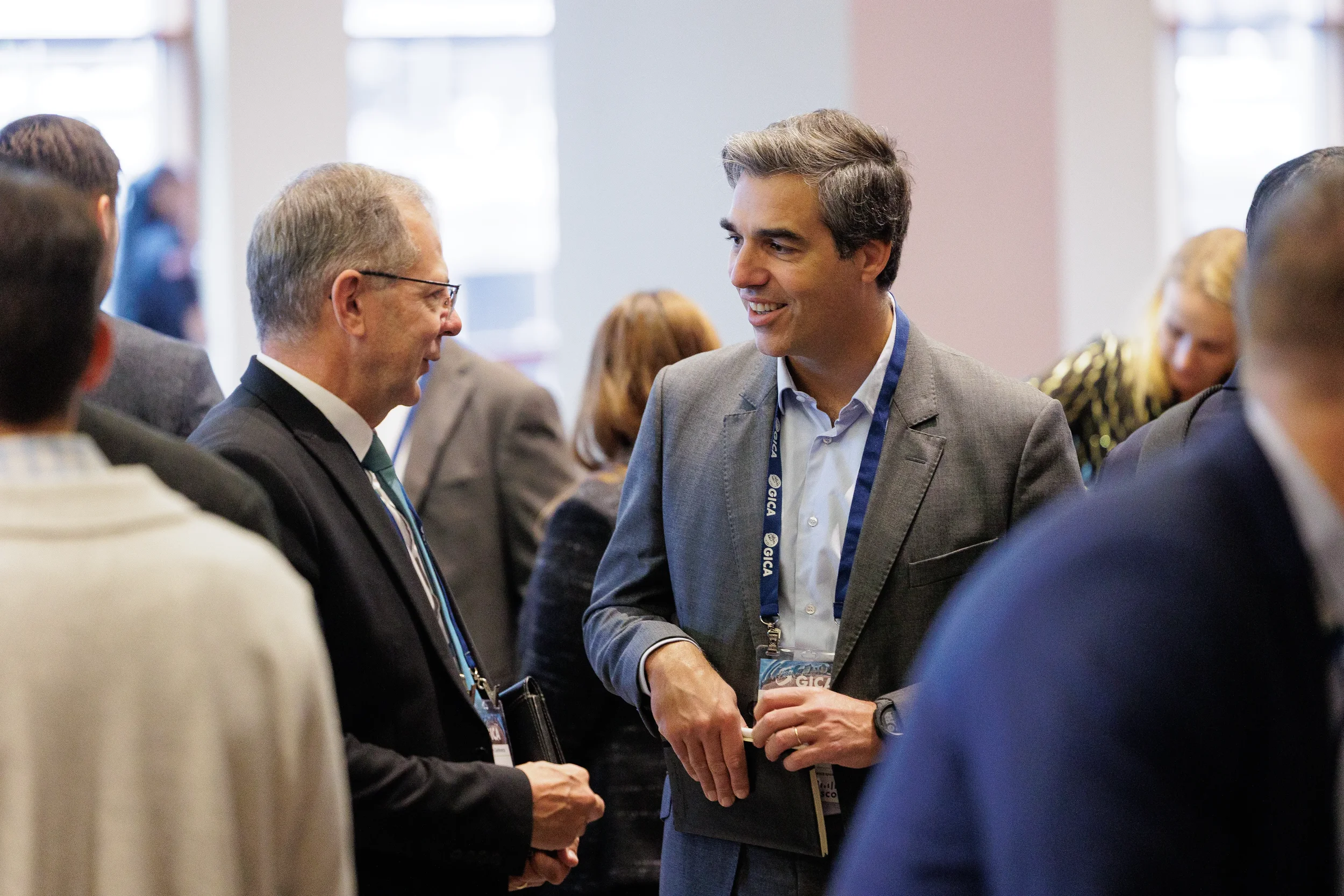 Two professionally dressed men converse at a crowded business conference in Orlando.