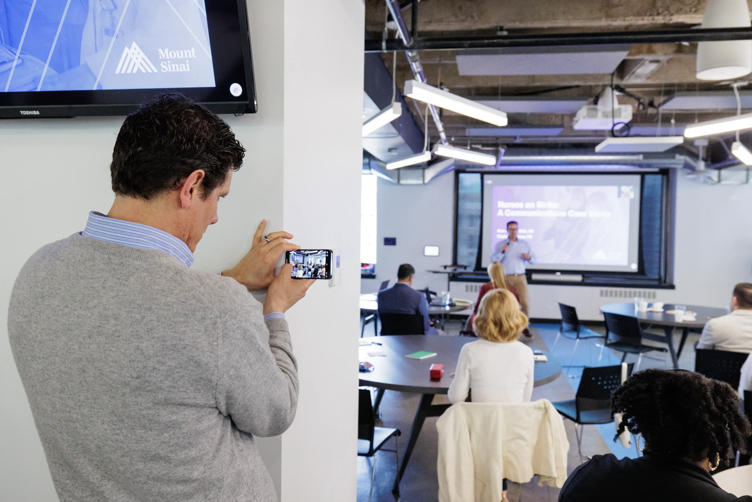 Attendee films a presenter on smartphone while others watch the session at Orlando corporate event
