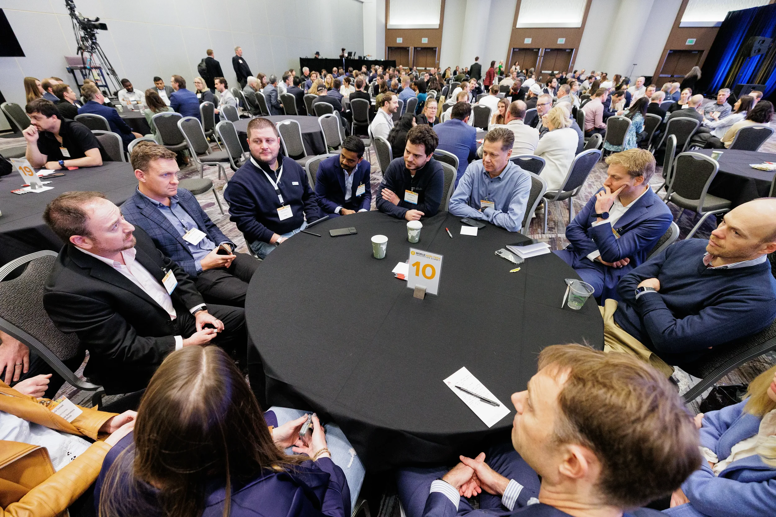 Large group of badged attendees engaged in discussion at round table during Chicago industry conference