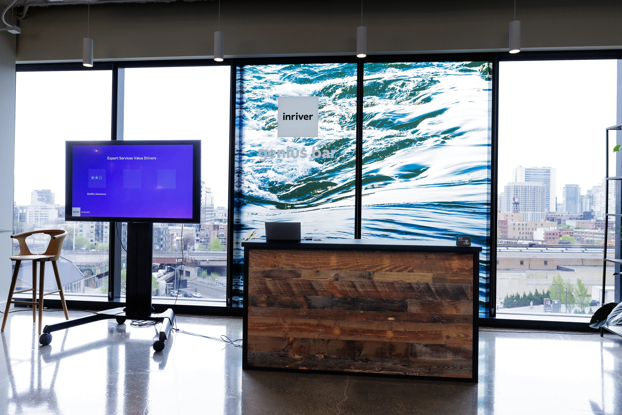 Branded expo booth with wood counter and display screen before city windows at Chicago conference
