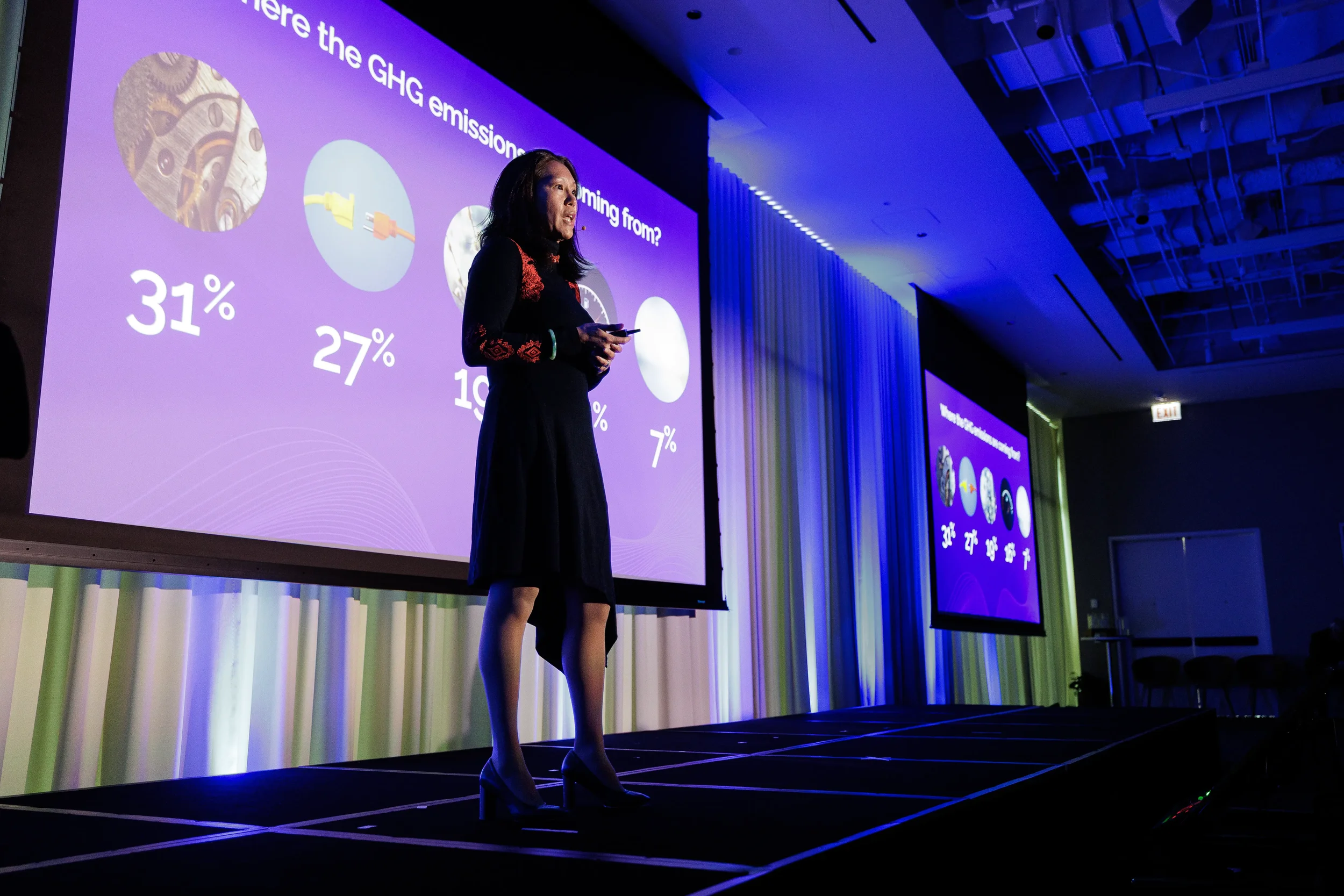 Speaker presents statistics slide on purple projection screen on stage at Chicago industry conference