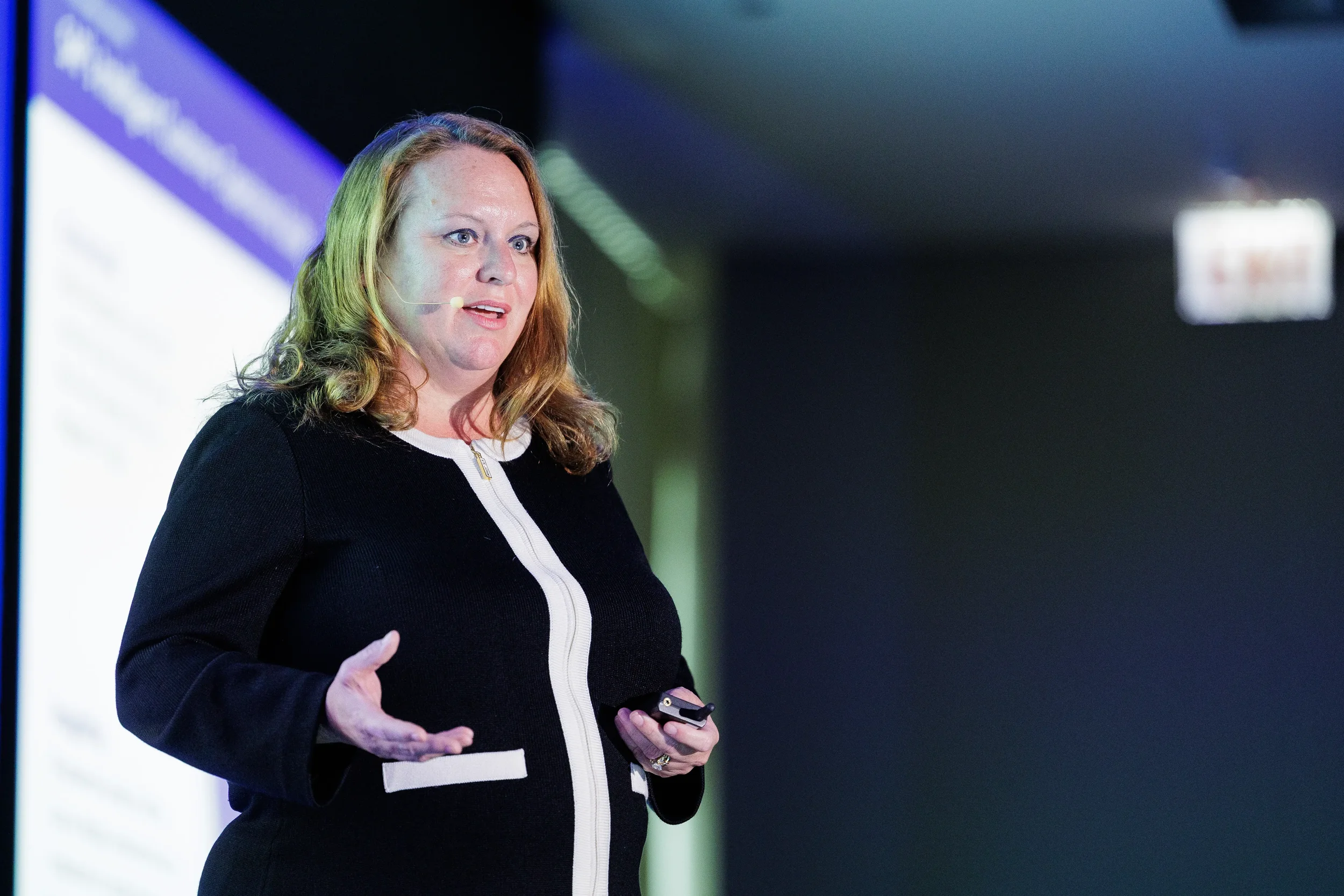 Speaker with headset microphone gestures while presenting on stage at Chicago corporate conference