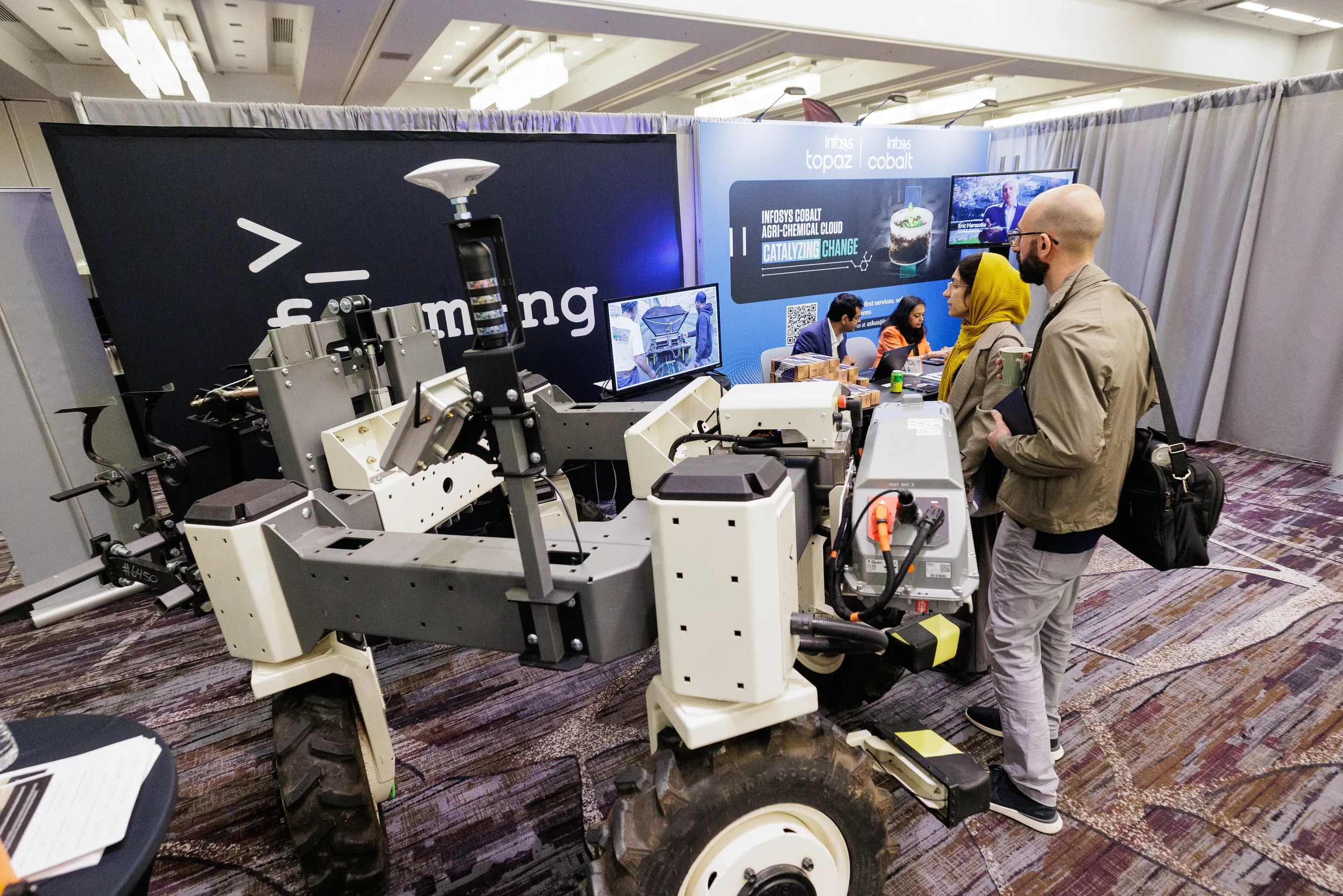 Attendees examine robotic farming equipment at exhibitor booth during Chicago industry conference