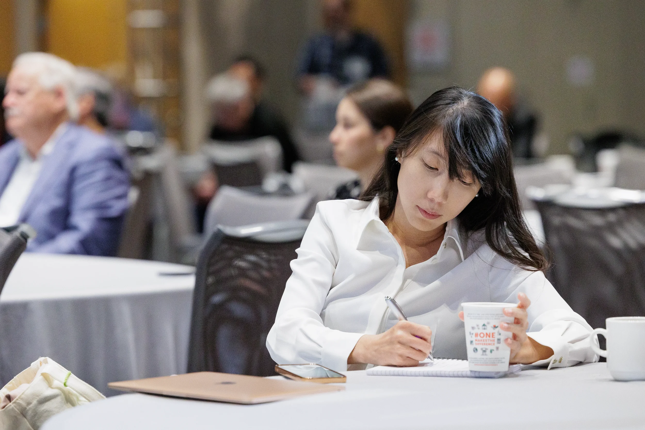 Attendee takes notes while seated at table during session at Orlando industry conference event