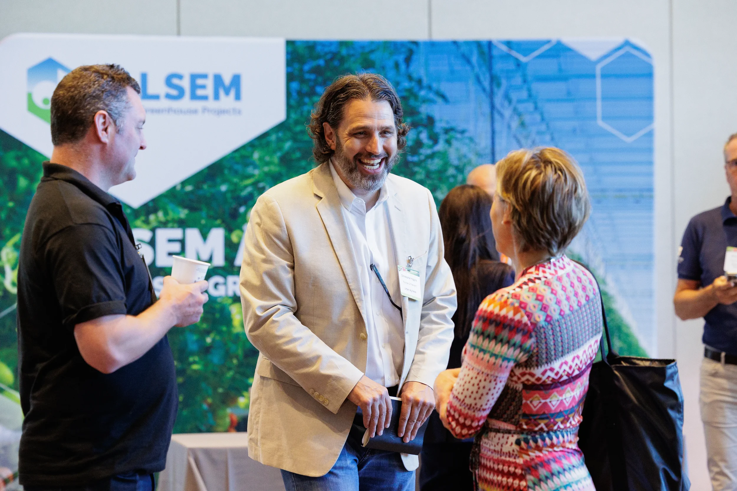Attendees laugh and network near exhibitor booth on expo floor at Orlando conference