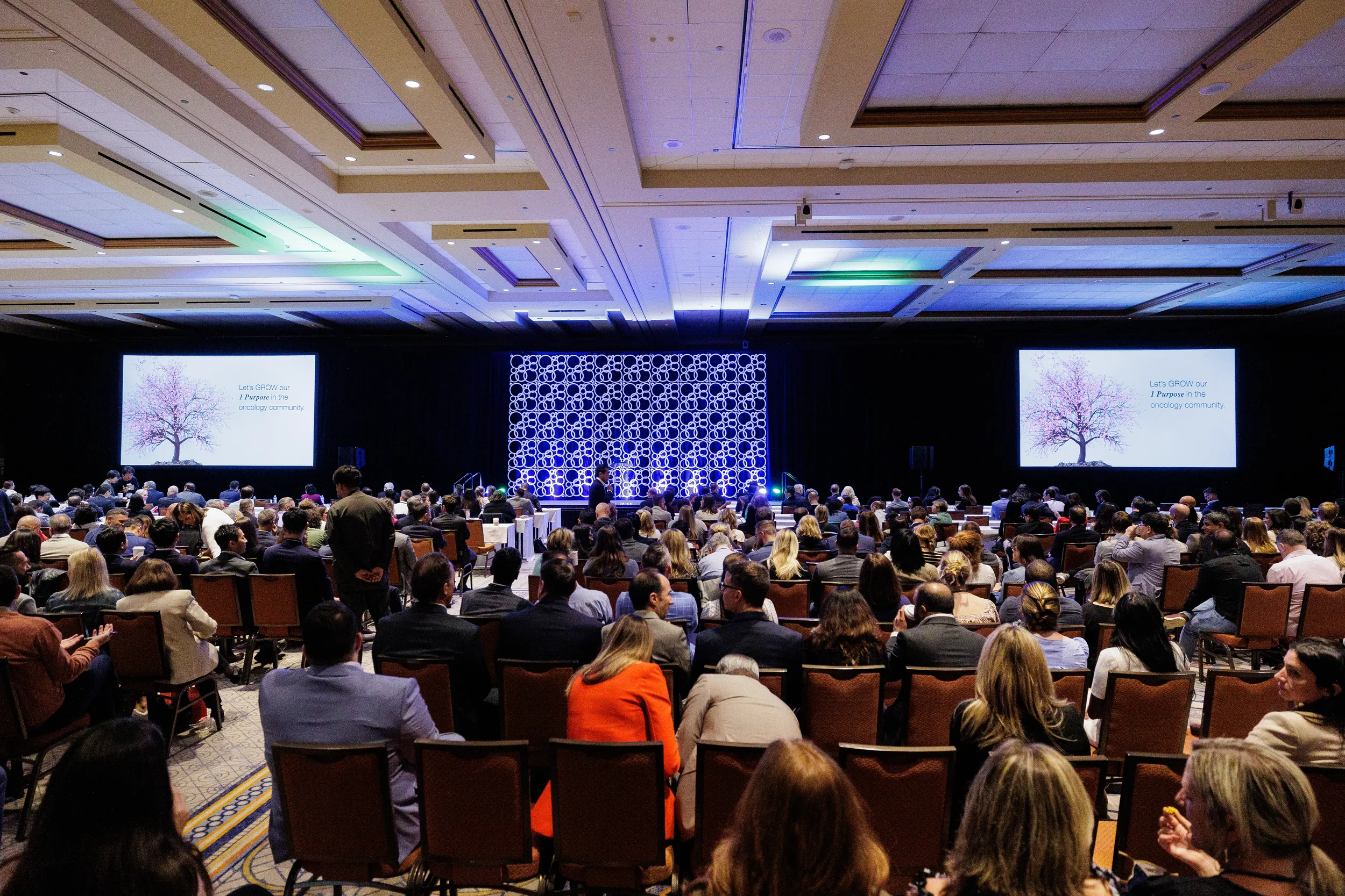 Wide view of audience watching presentation on dual screens in ballroom at Chicago conference