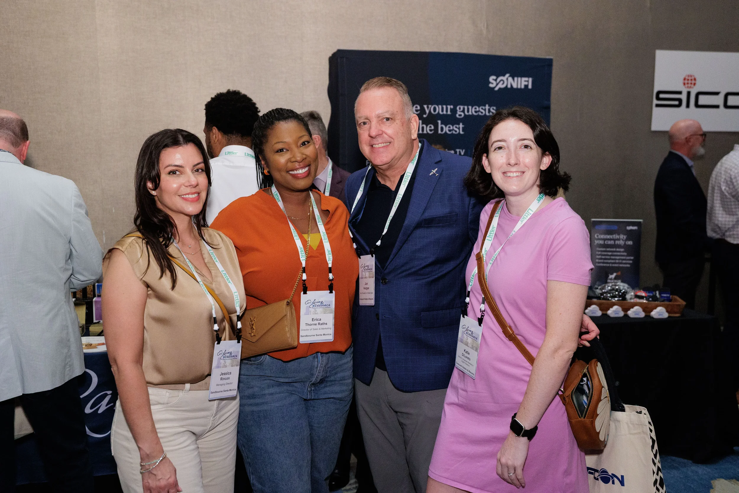 Four attendees with lanyards pose together smiling on Chicago corporate conference expo floor