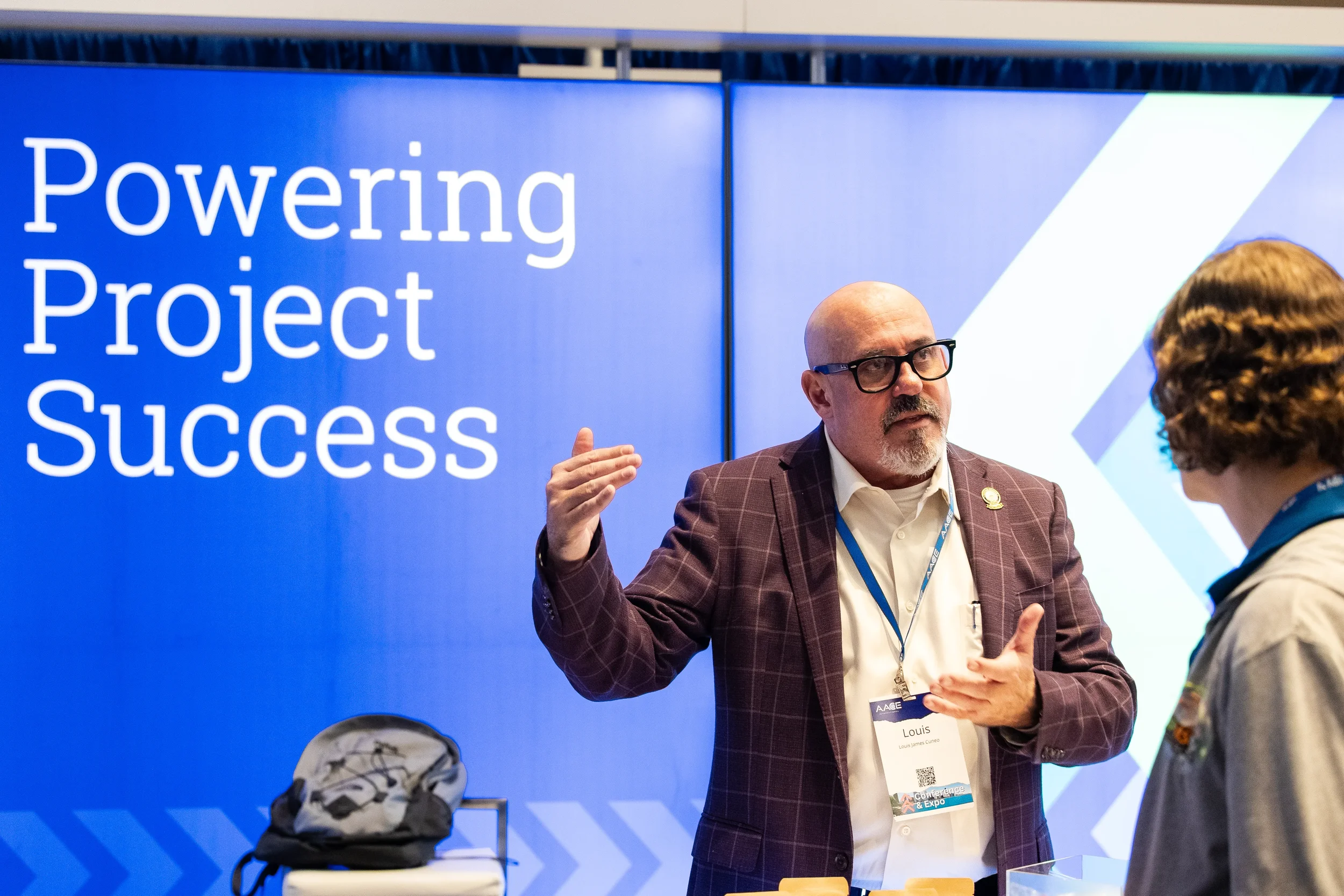 Trade show exhibitor gesturing while speaking with attendee at Chicago conference expo booth