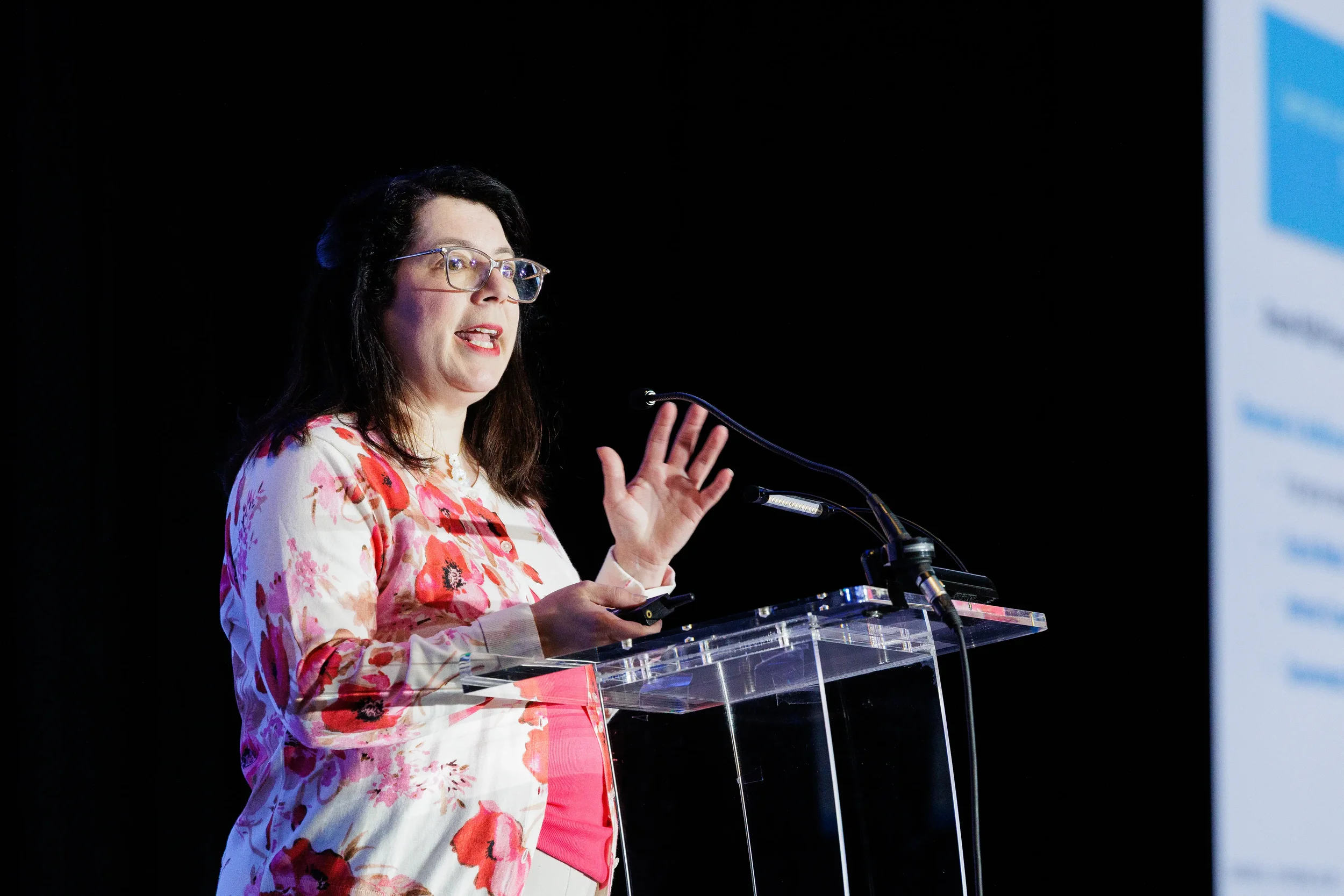 Speaker gestures while presenting from podium on stage at Orlando corporate conference
