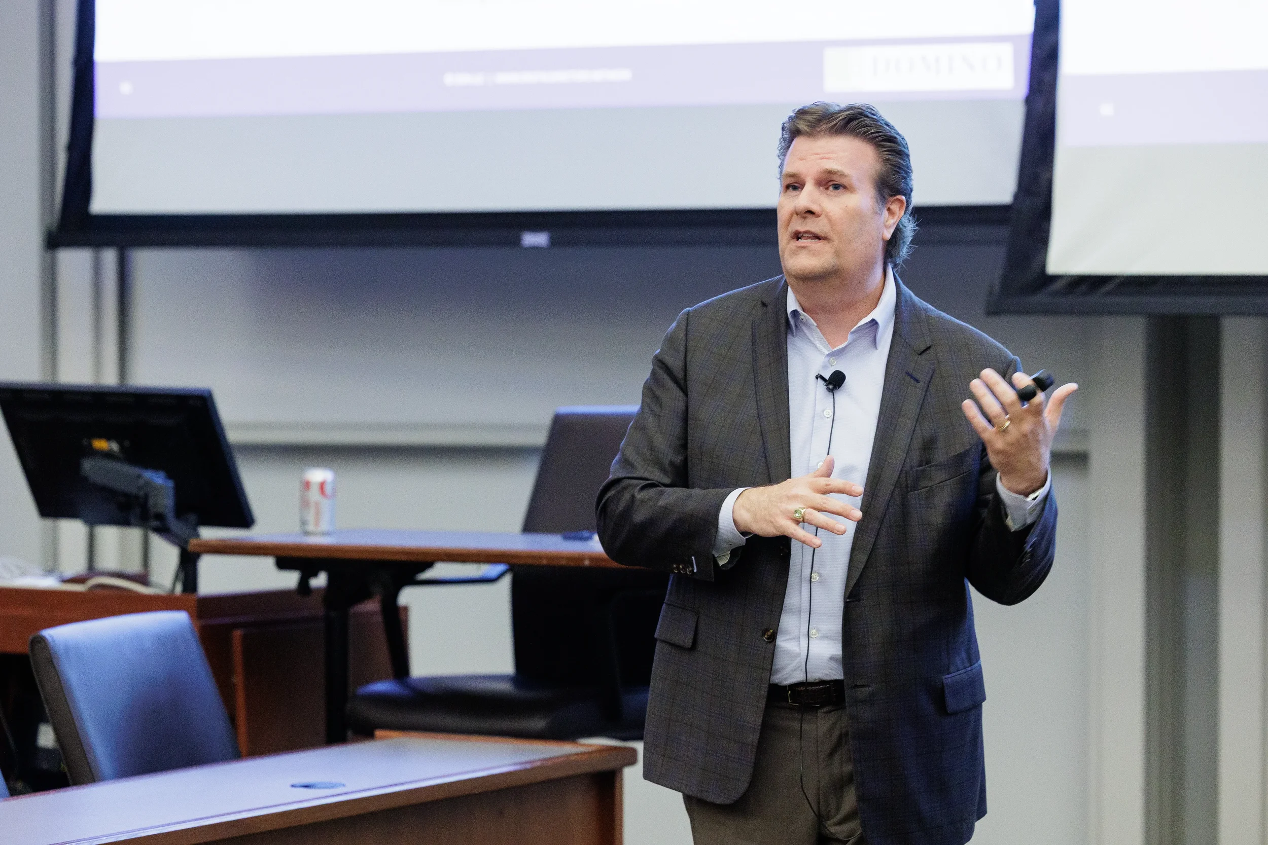 Speaker gestures with clicker in front of dual projection screens at Orlando corporate conference