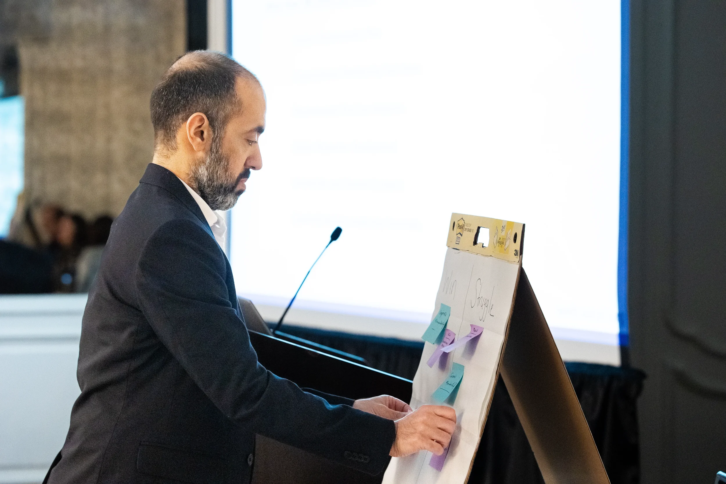 Workshop presenter arranges sticky notes on easel during interactive session at Chicago conference