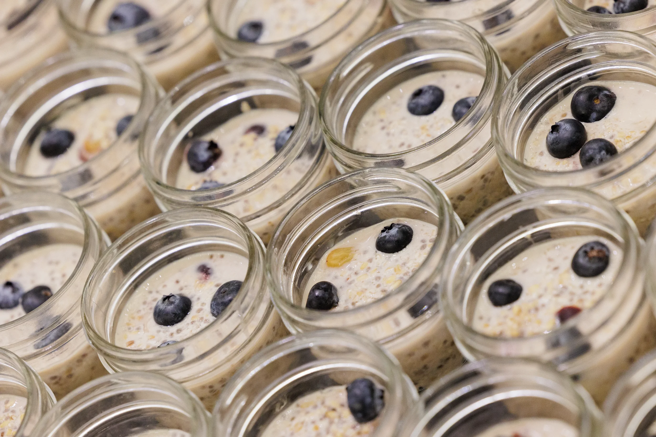 Rows of individual overnight oat jars topped with blueberries at Chicago corporate event catering station