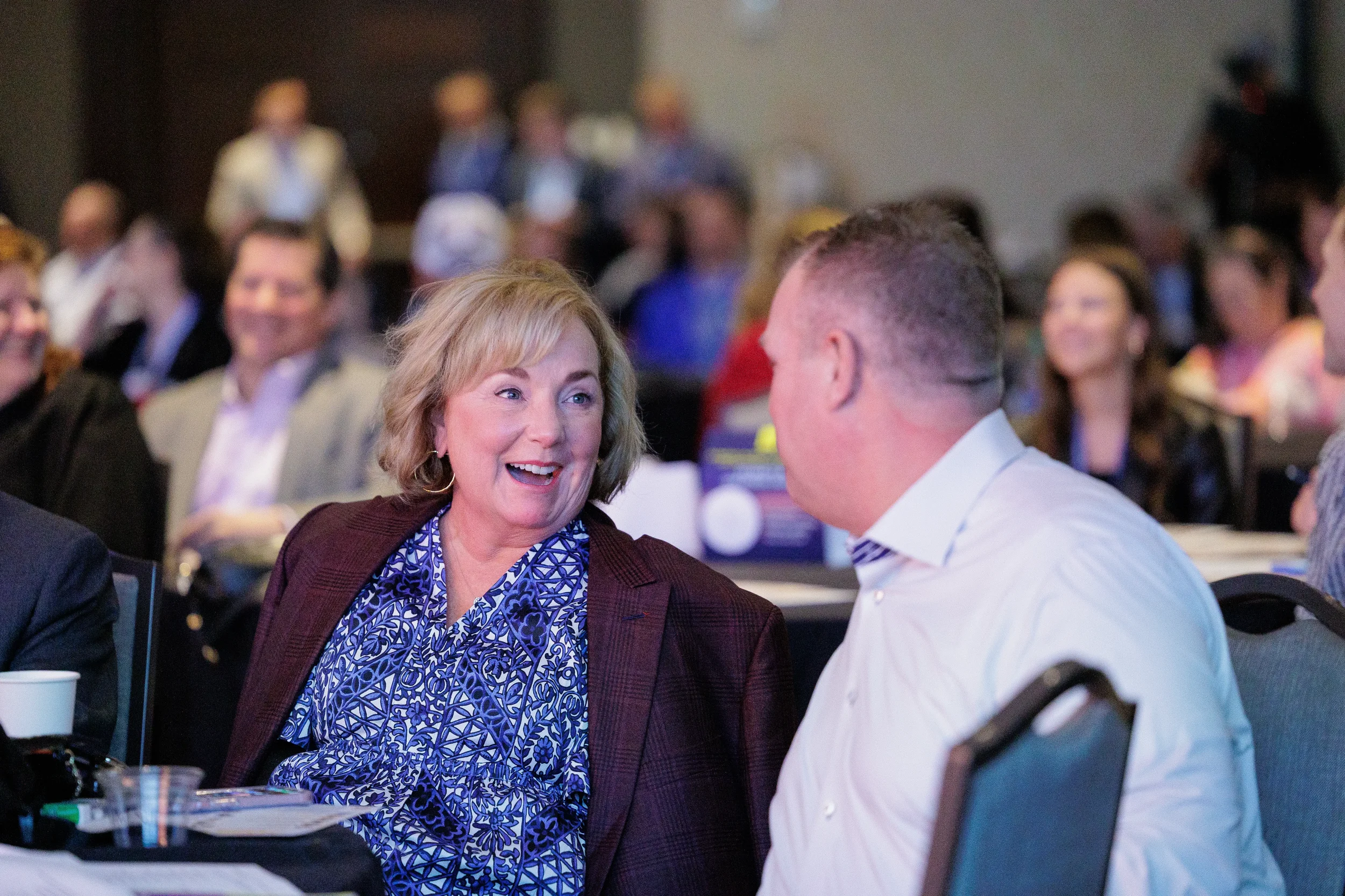 Two attendees laugh together in animated conversation at table during Chicago corporate conference event