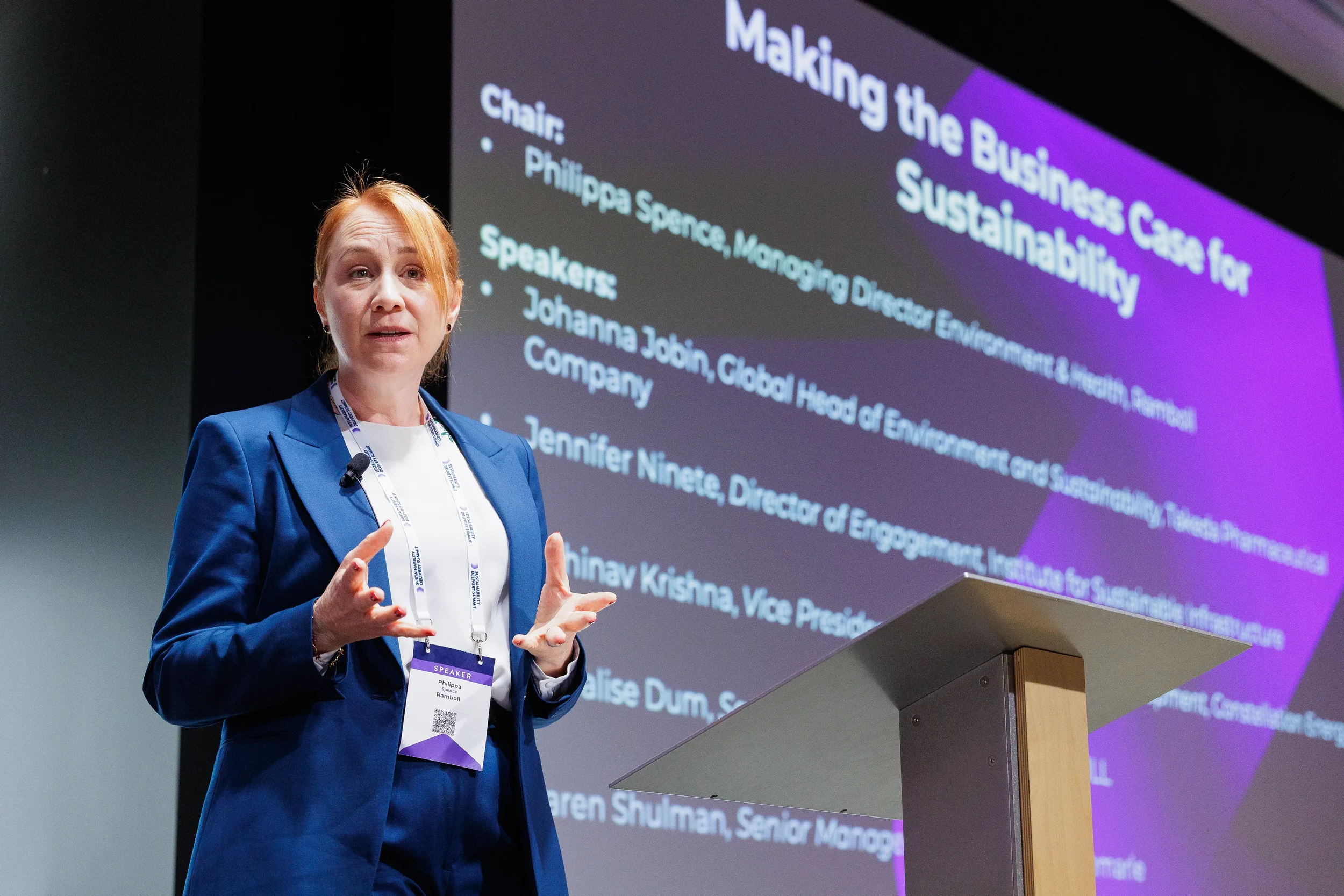 Speaker gestures while presenting from podium on screen at Chicago industry conference