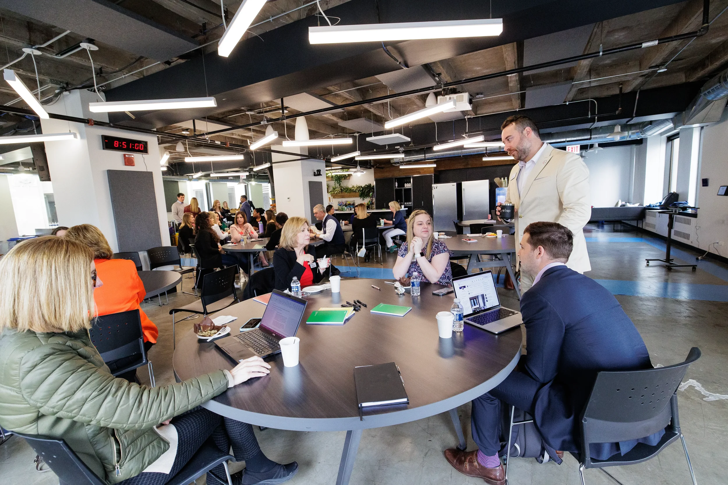 Wide view of attendees seated at round tables with laptops across a full Chicago corporate event venue