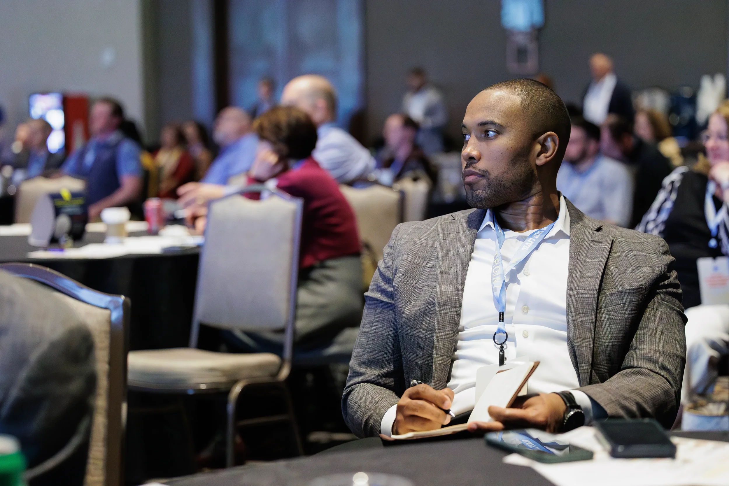 Attendee in suit holds notebook and listens attentively during session at Chicago corporate conference event