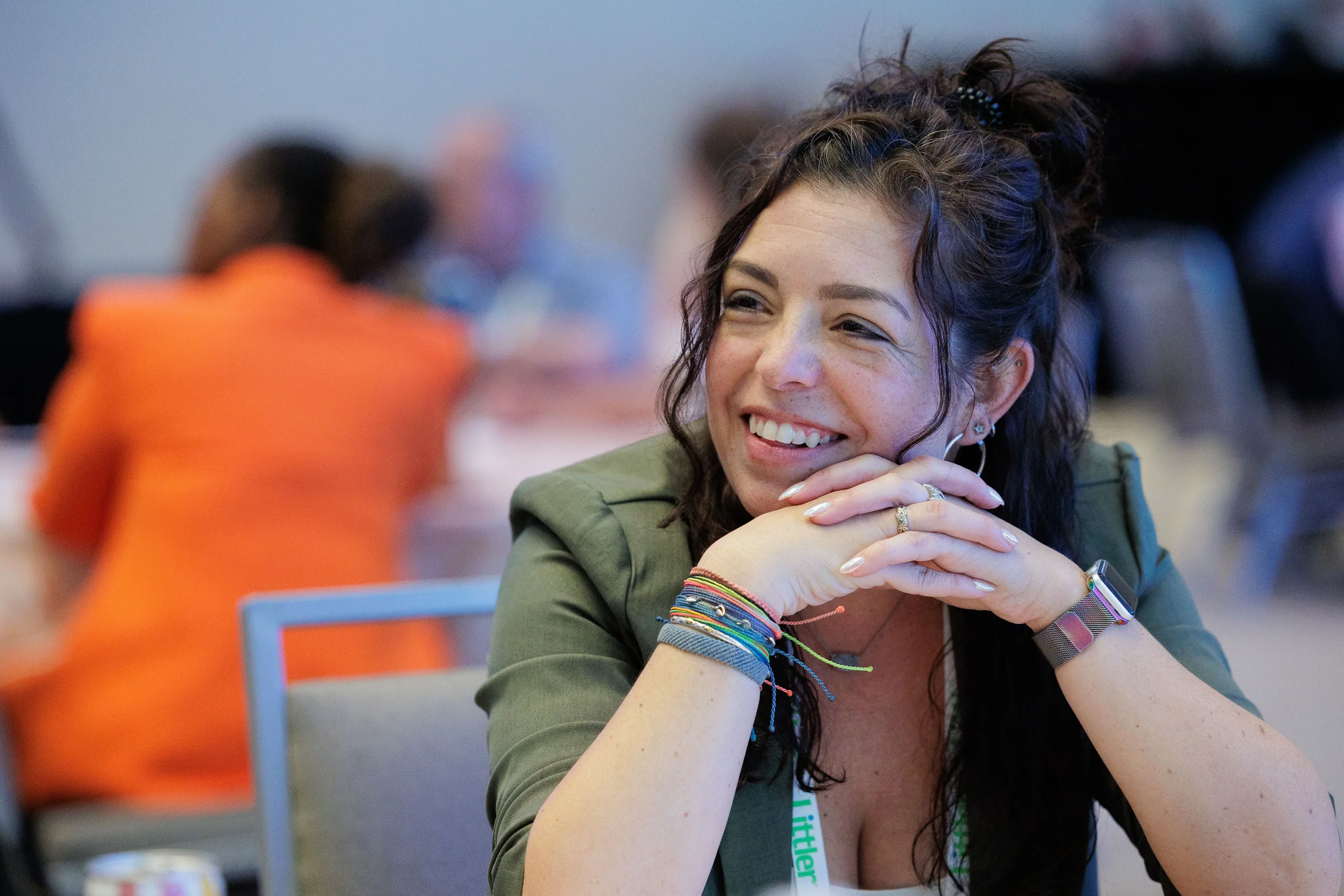 Female attendee with lanyard smiles warmly while seated during Chicago corporate conference session