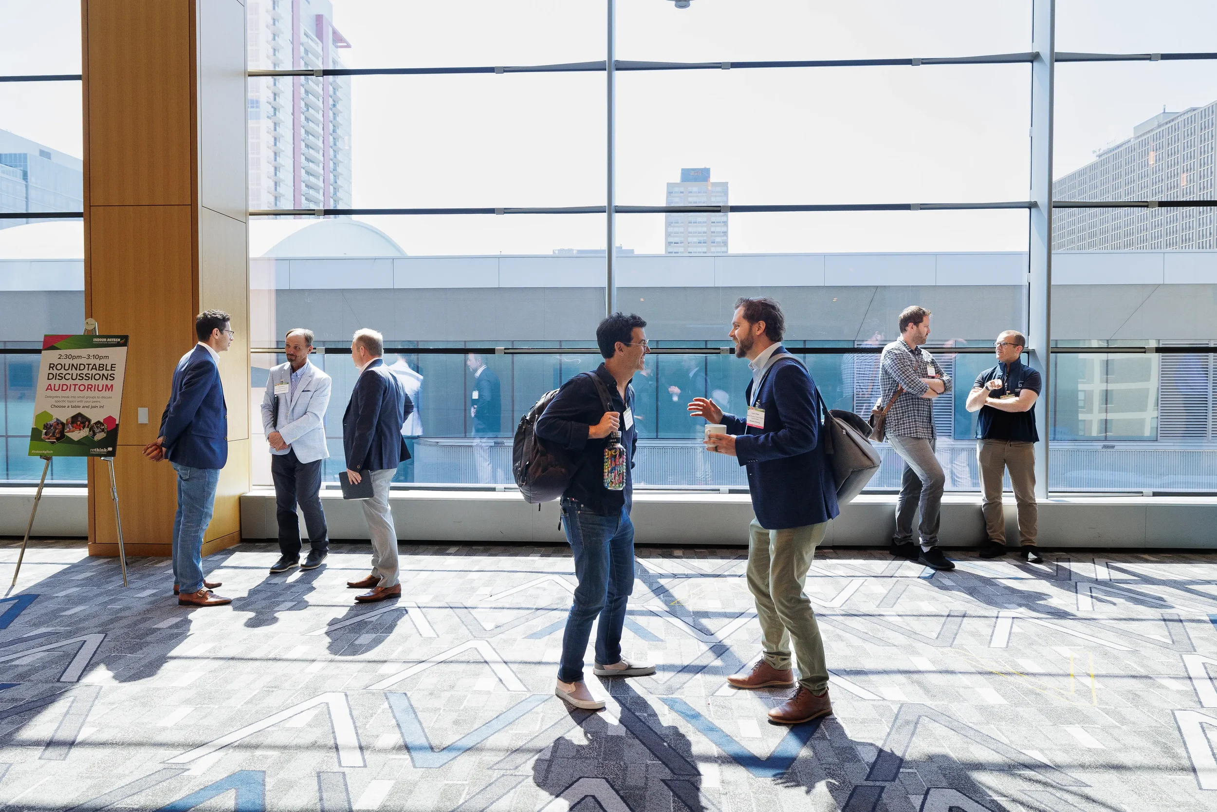 Attendees converse in conference hallway with city skyline visible at Chicago industry conference event