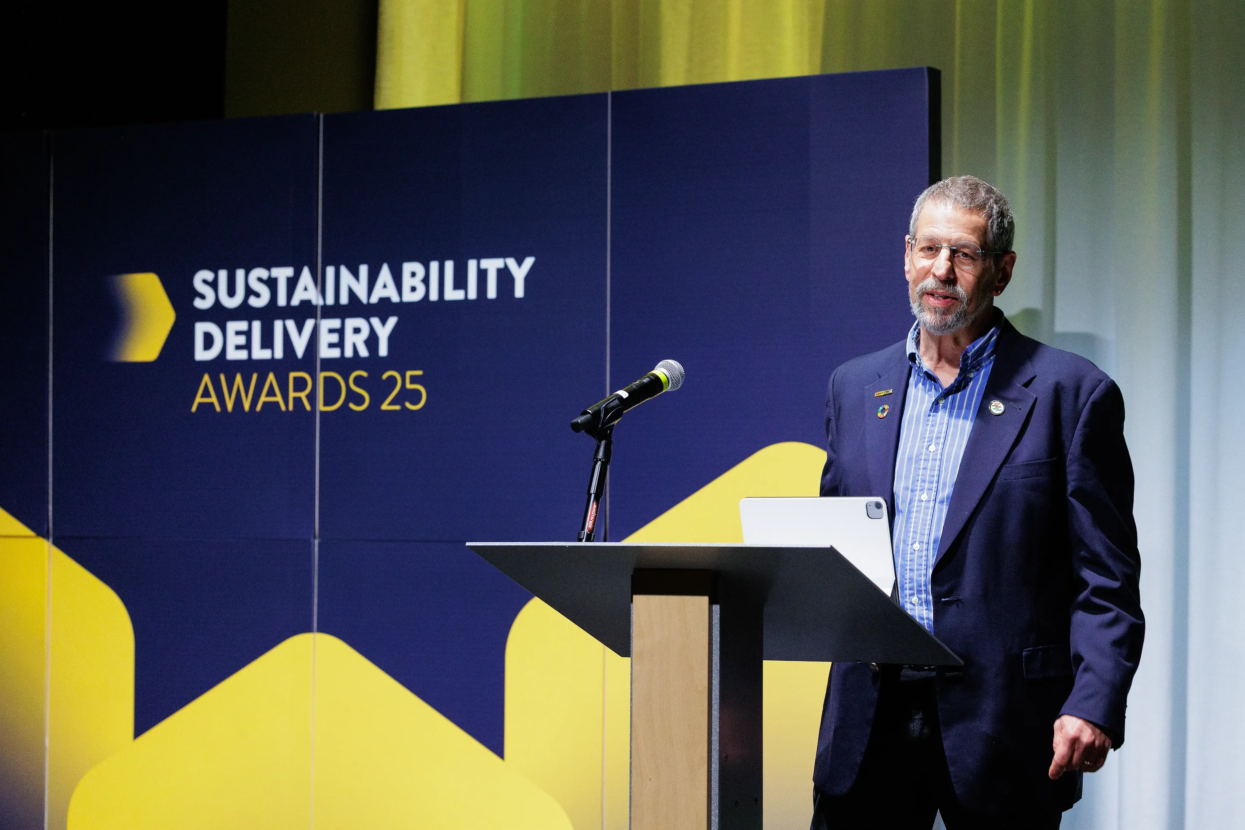 Speaker addresses audience from podium with branded backdrop at Chicago awards ceremony