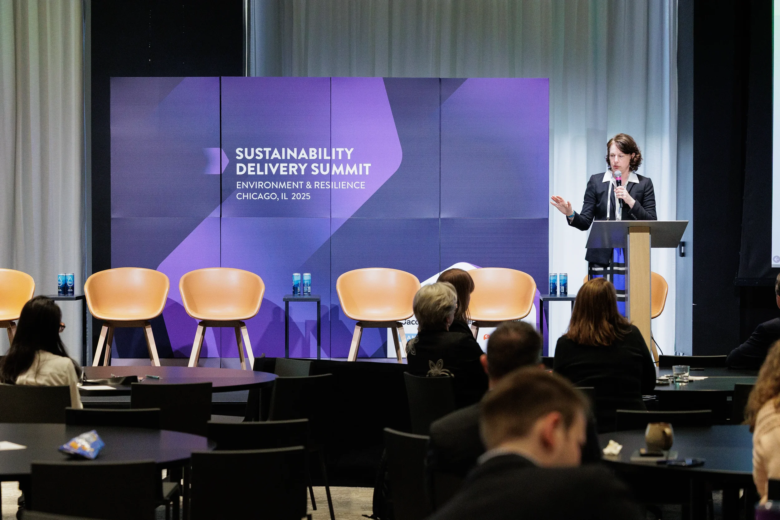 Speaker addresses audience from podium in front of branded backdrop at Orlando industry summit