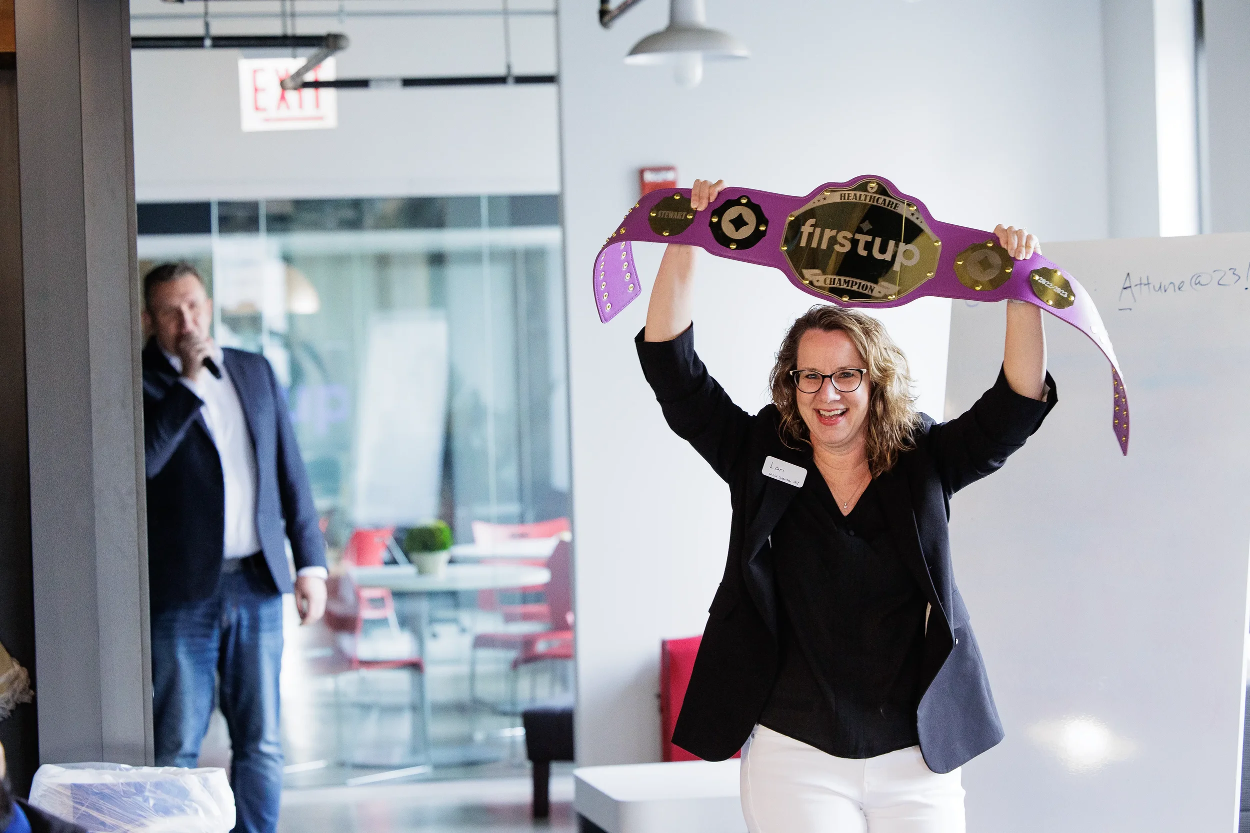 Female attendee raises a branded champion belt overhead in celebration at Chicago corporate event