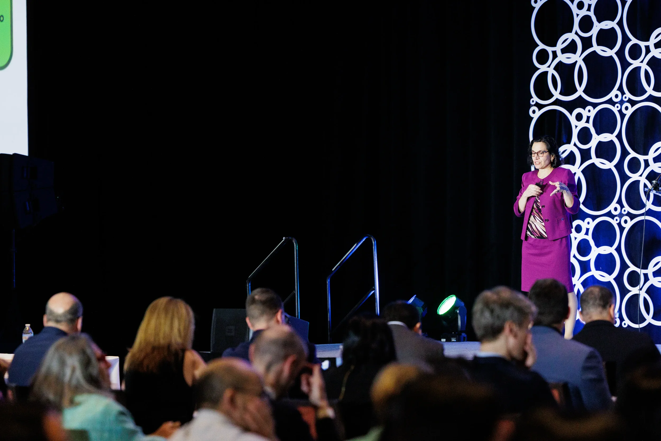 Speaker presents on stage with branded circle backdrop at Chicago industry conference
