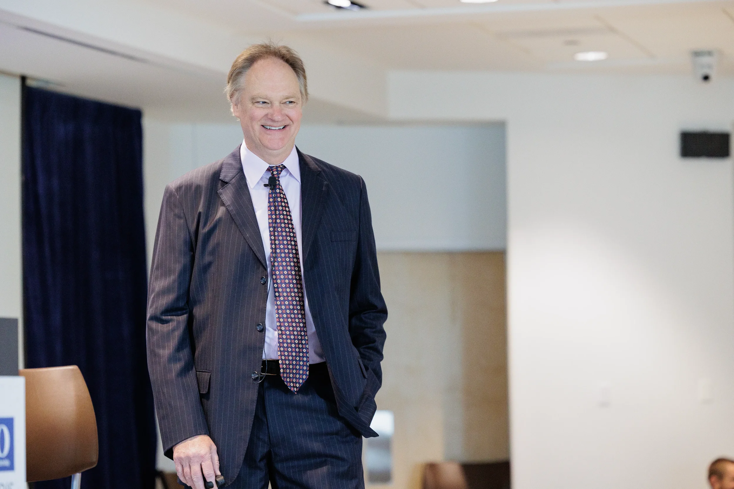 Smiling male speaker stands confidently on stage during Chicago industry conference session