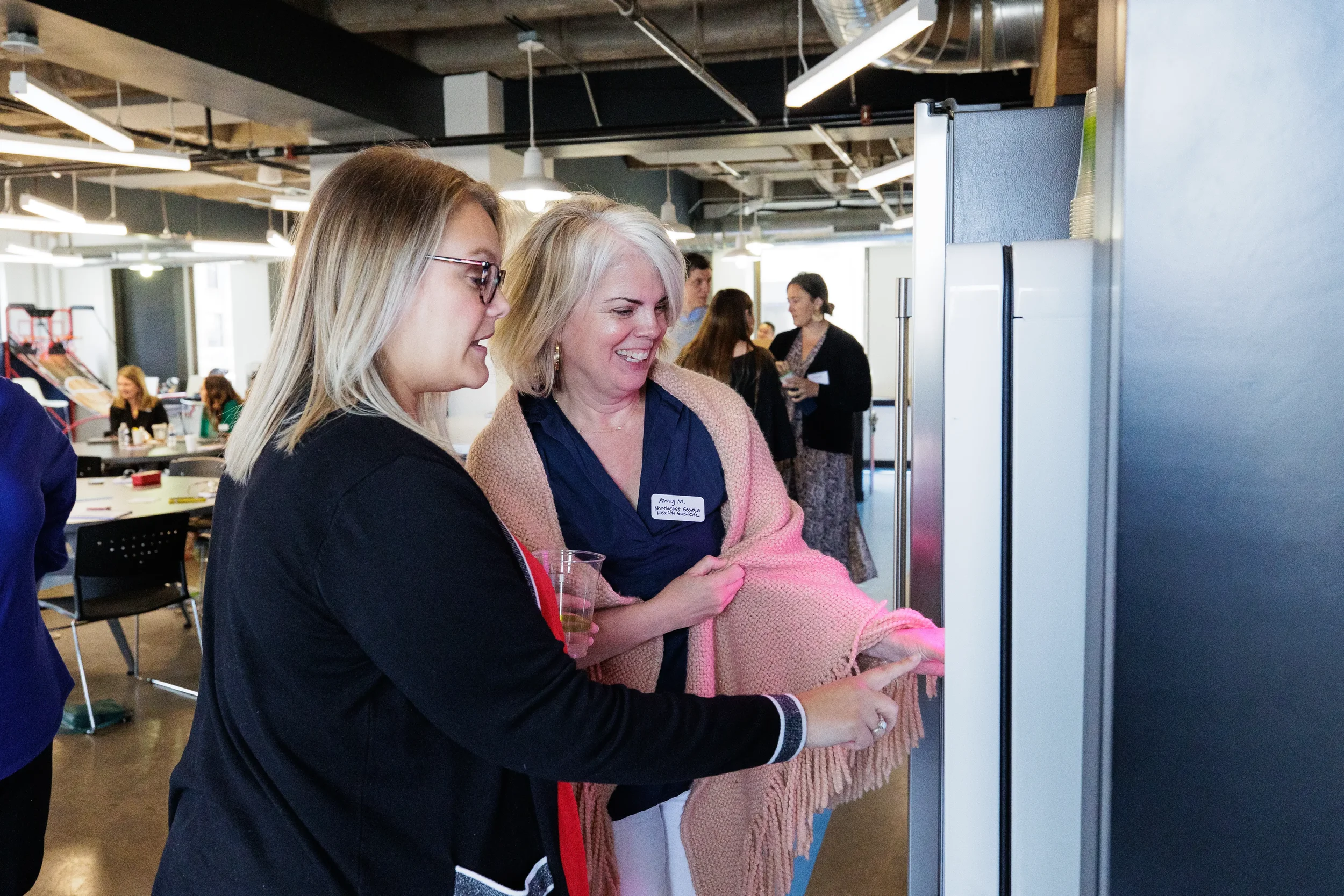 Two attendees smile while examining a display together during a networking break at Chicago conference