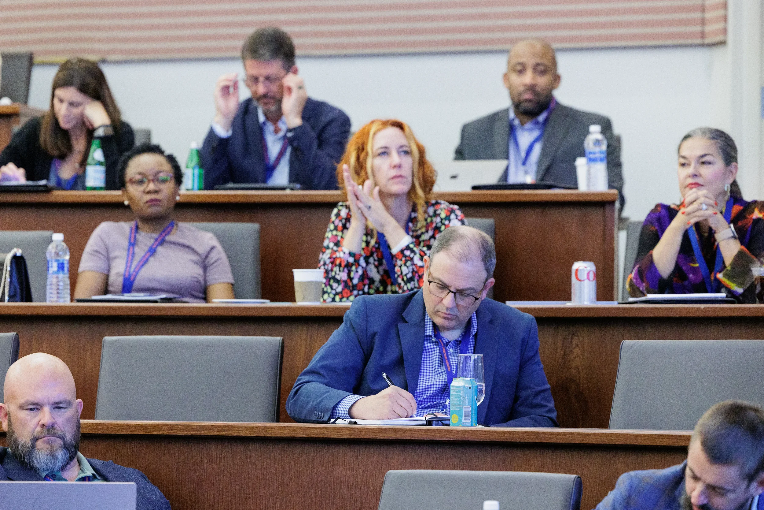 Attendees with lanyards take notes and listen attentively in tiered lecture hall at Orlando industry conference