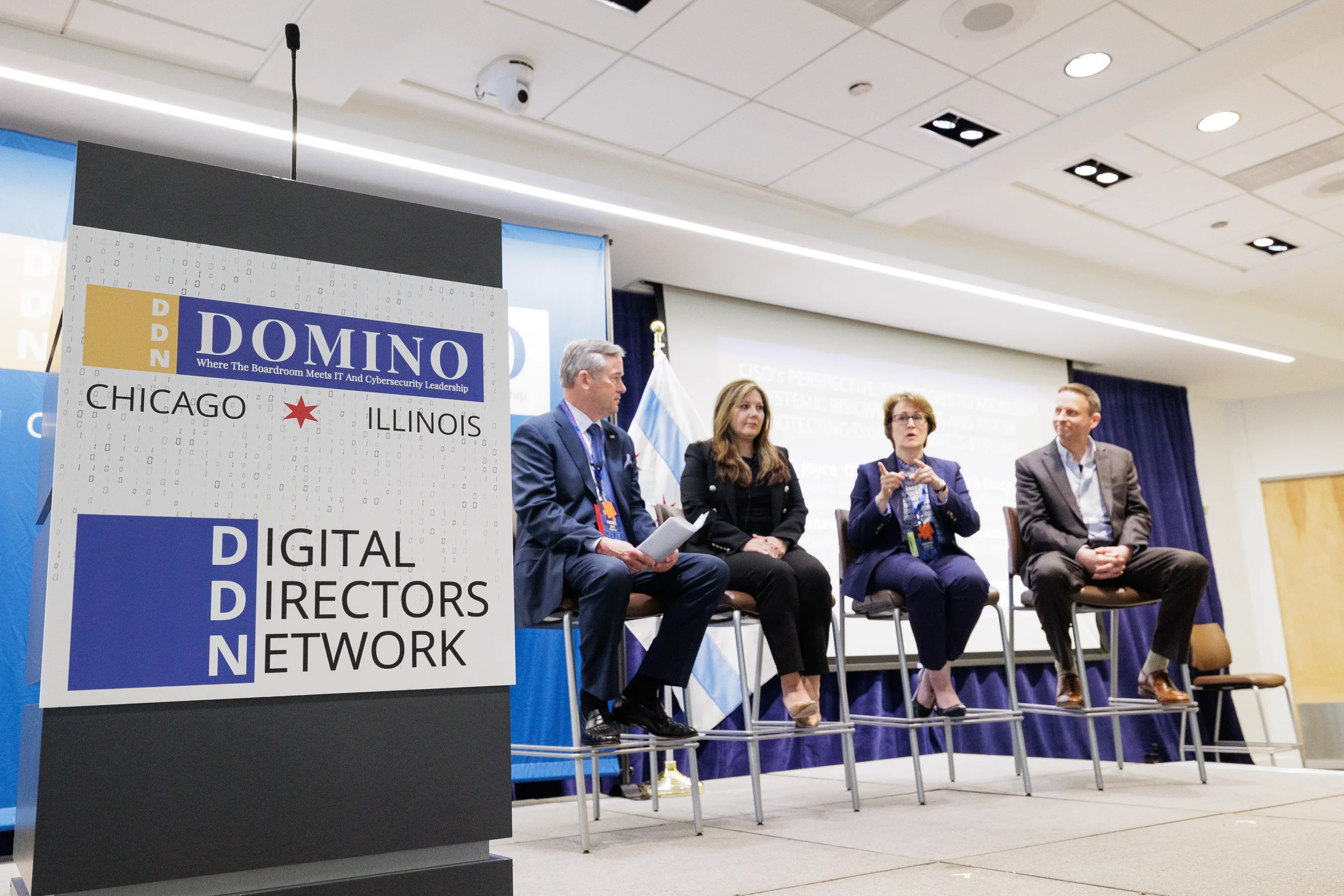 Four panelists seated on stage beside branded podium at Chicago corporate conference panel discussion