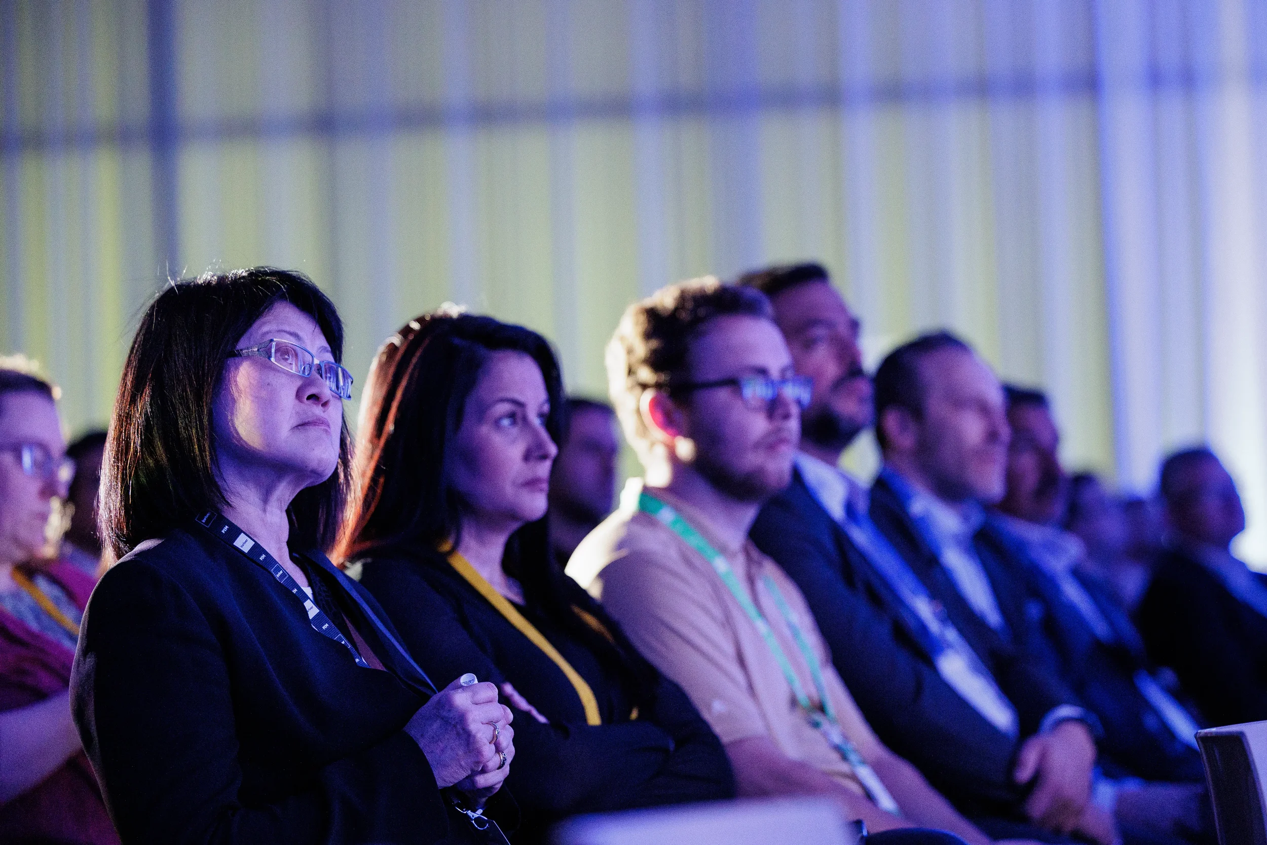 Close-up of attentive audience members with lanyards watching session at Chicago industry conference
