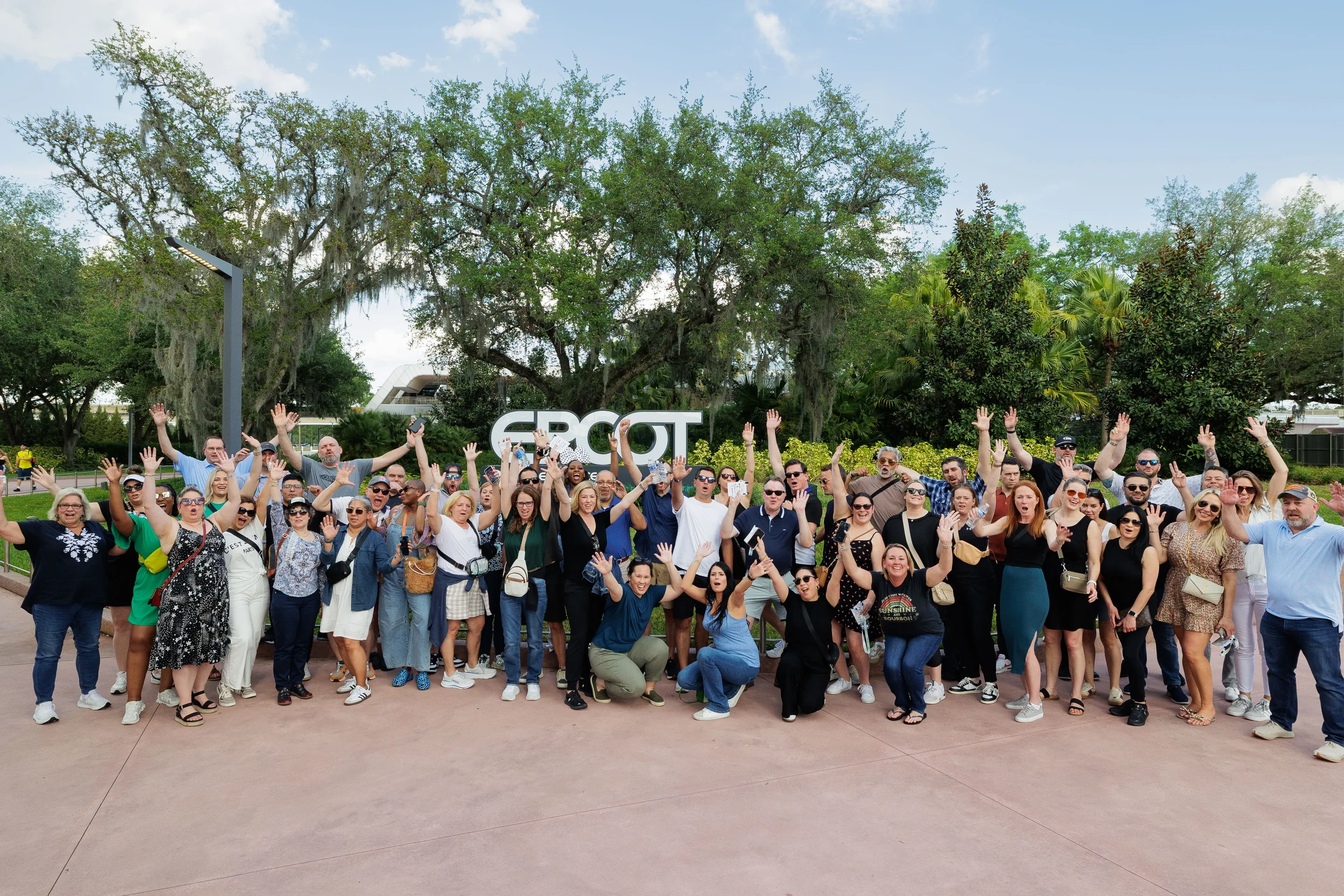 Large group of corporate conference attendees cheer together outdoors at Orlando industry event