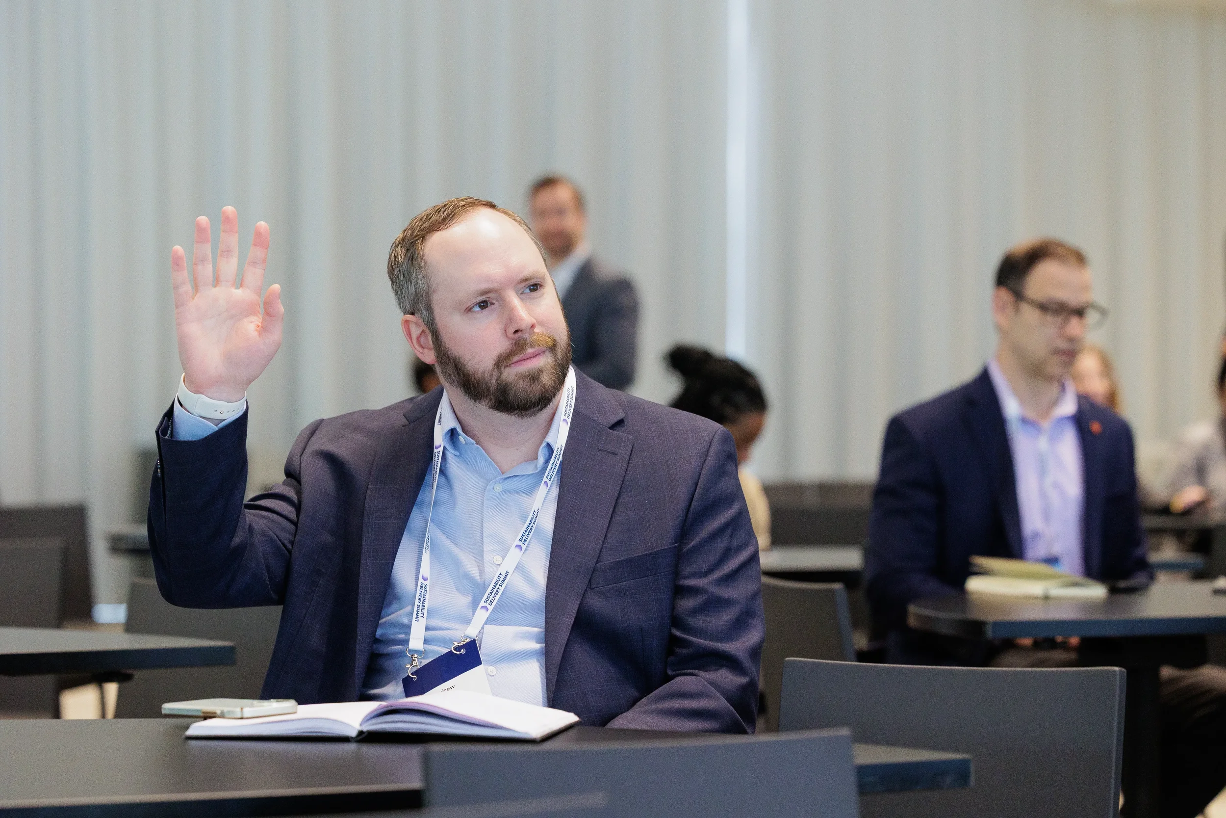 Attendee raises hand to ask question during seated session at Chicago industry conference
